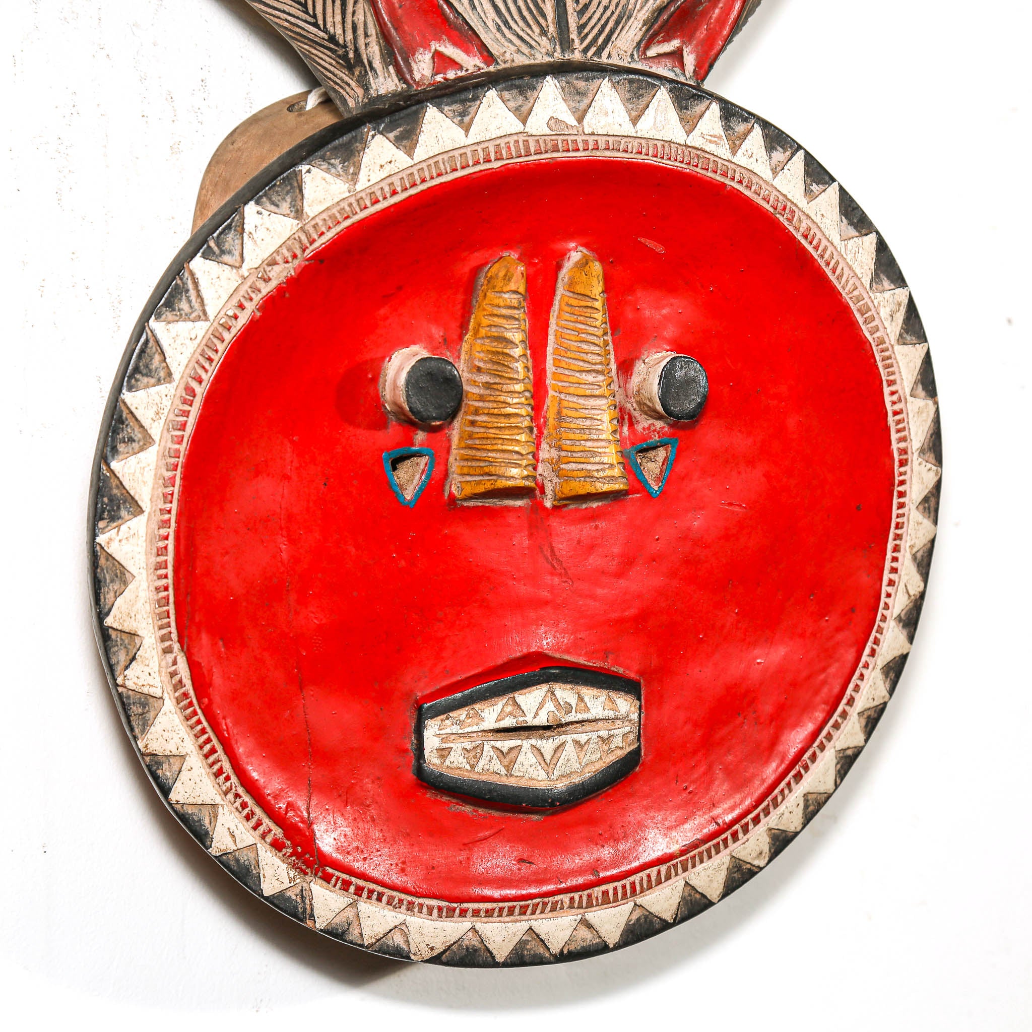 Decorative mask with red background and intricate patterns on a white background