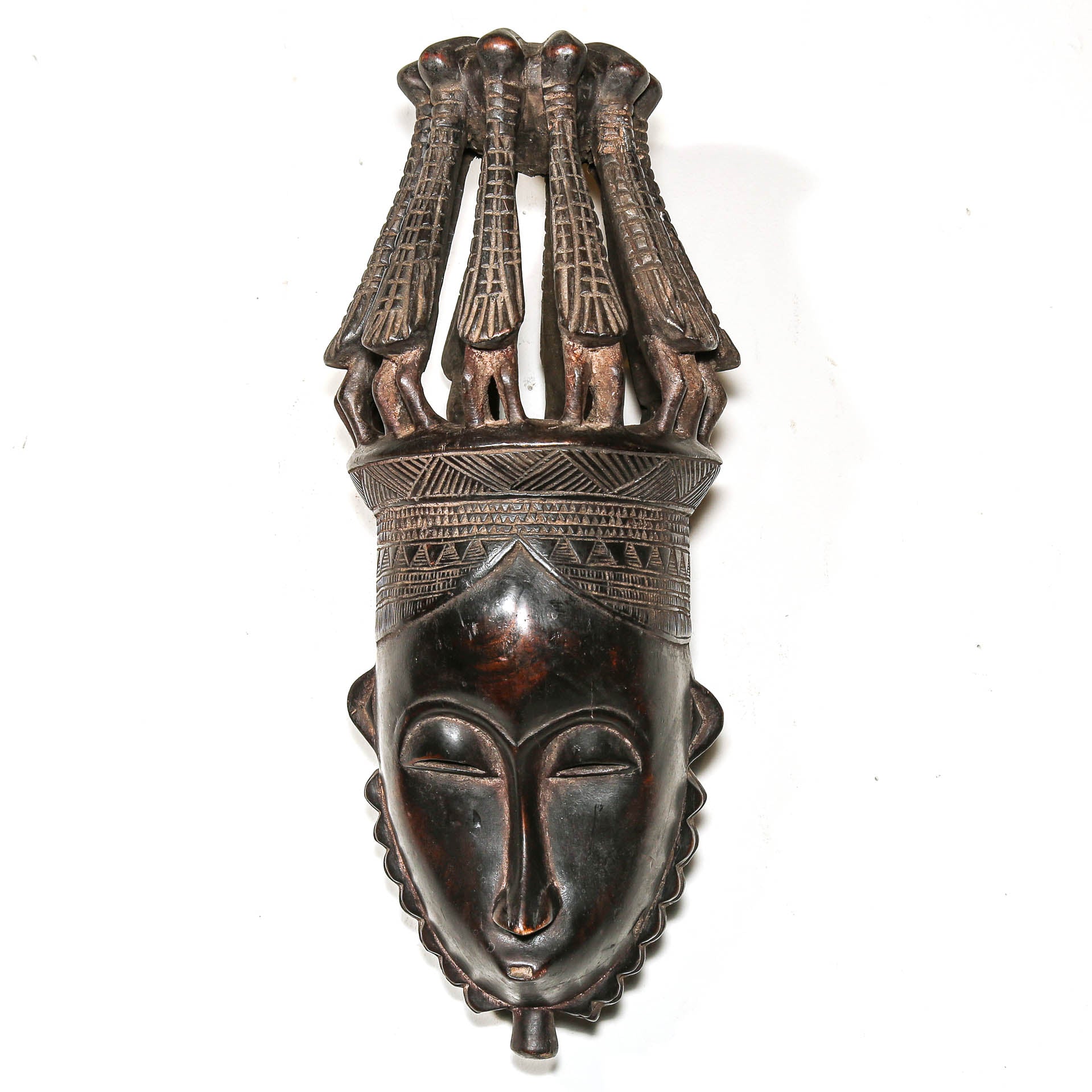 Black African mask with bird headdress on a white wall