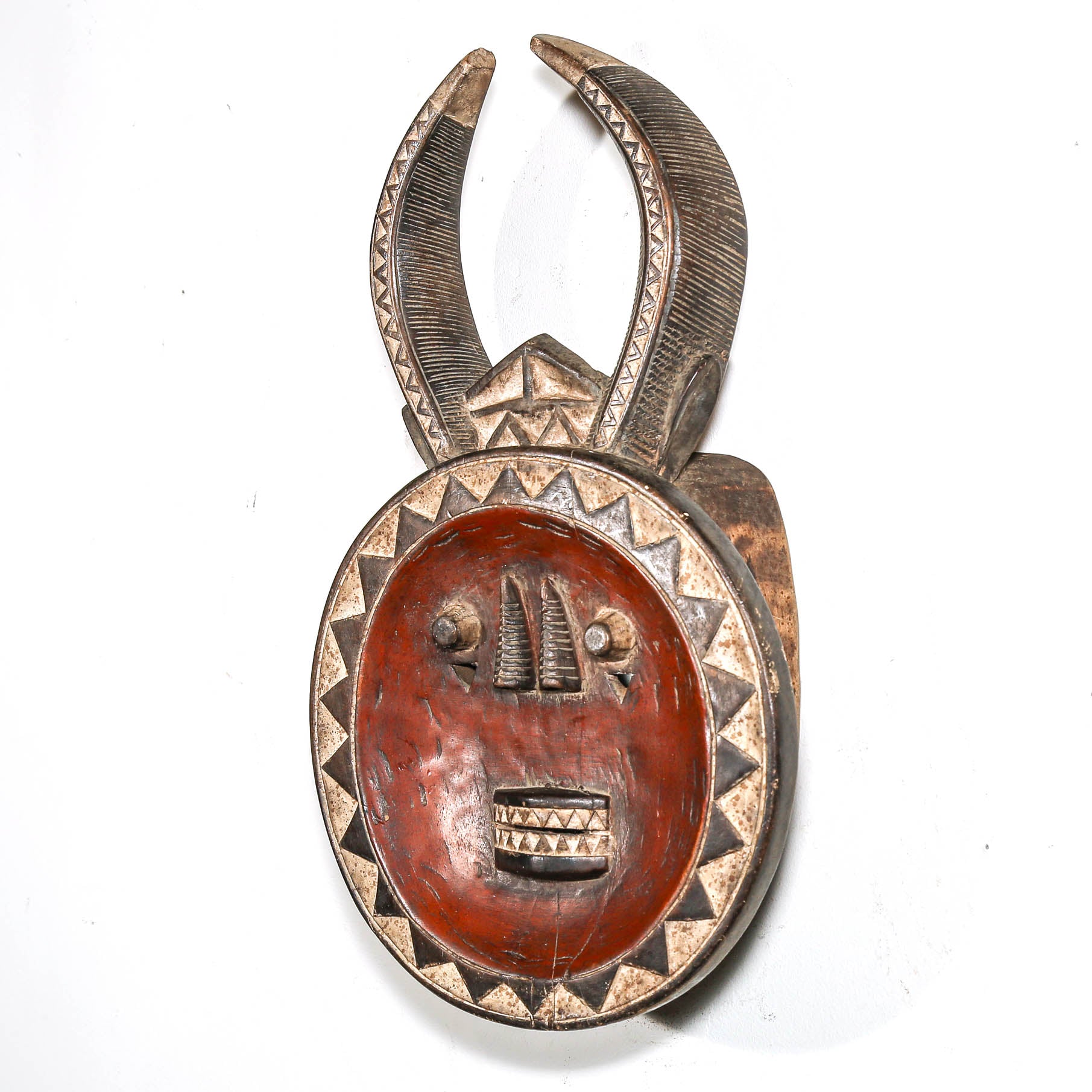 Decorative tribal African mask with horn-like structures on a white background