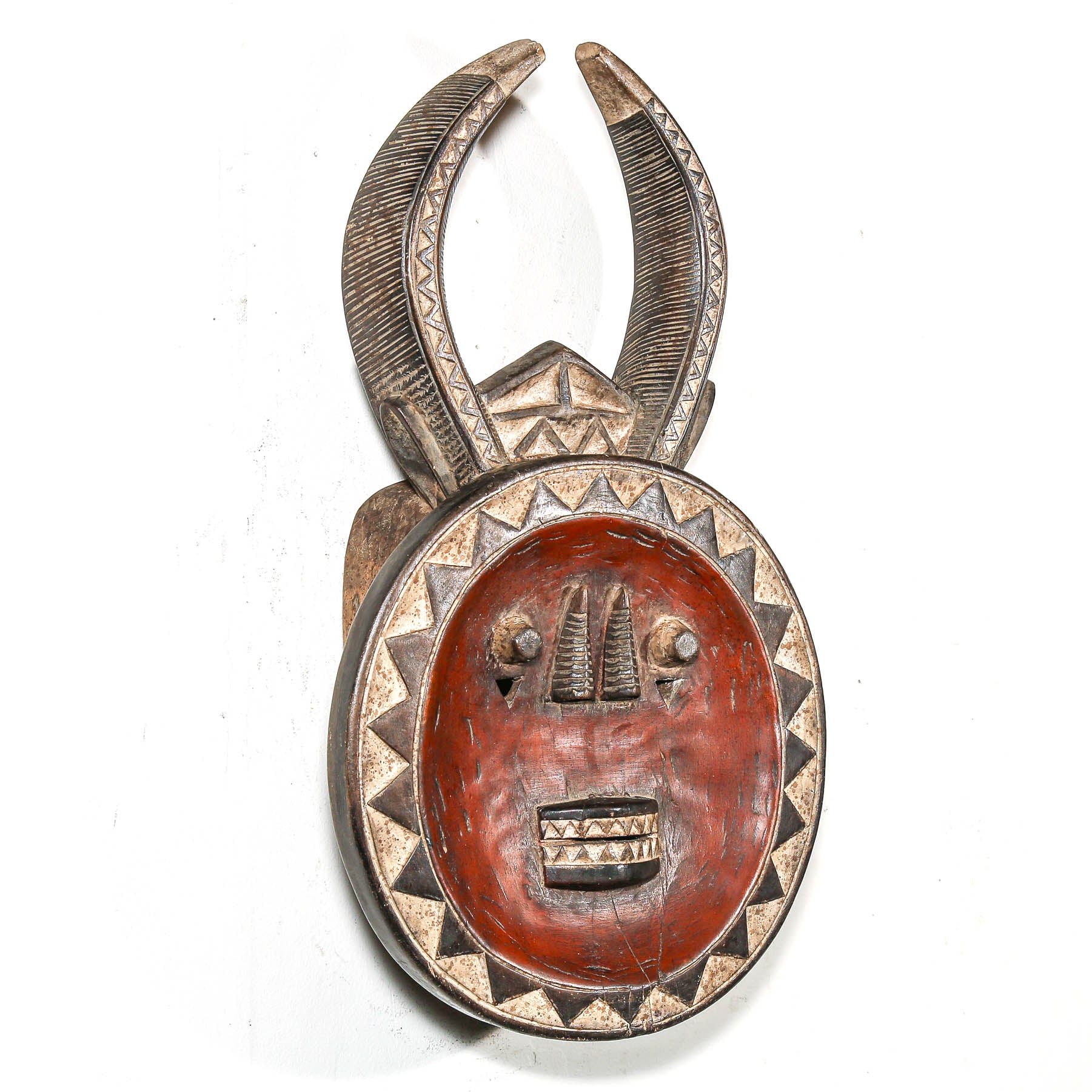 Decorative tribal African mask with horn-like structures on a white background