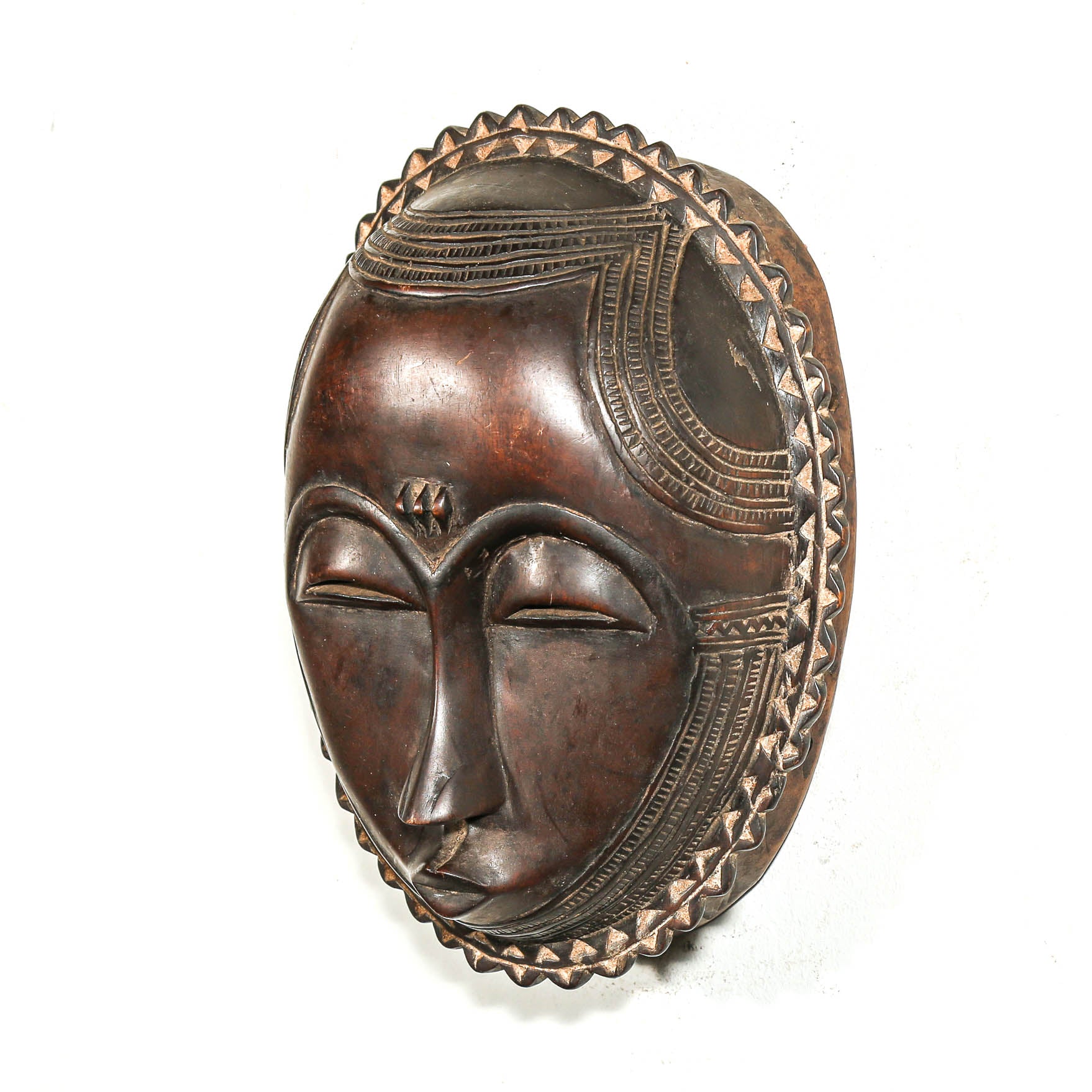 Decorative tribal mask with intricate designs on a white bedroom wall