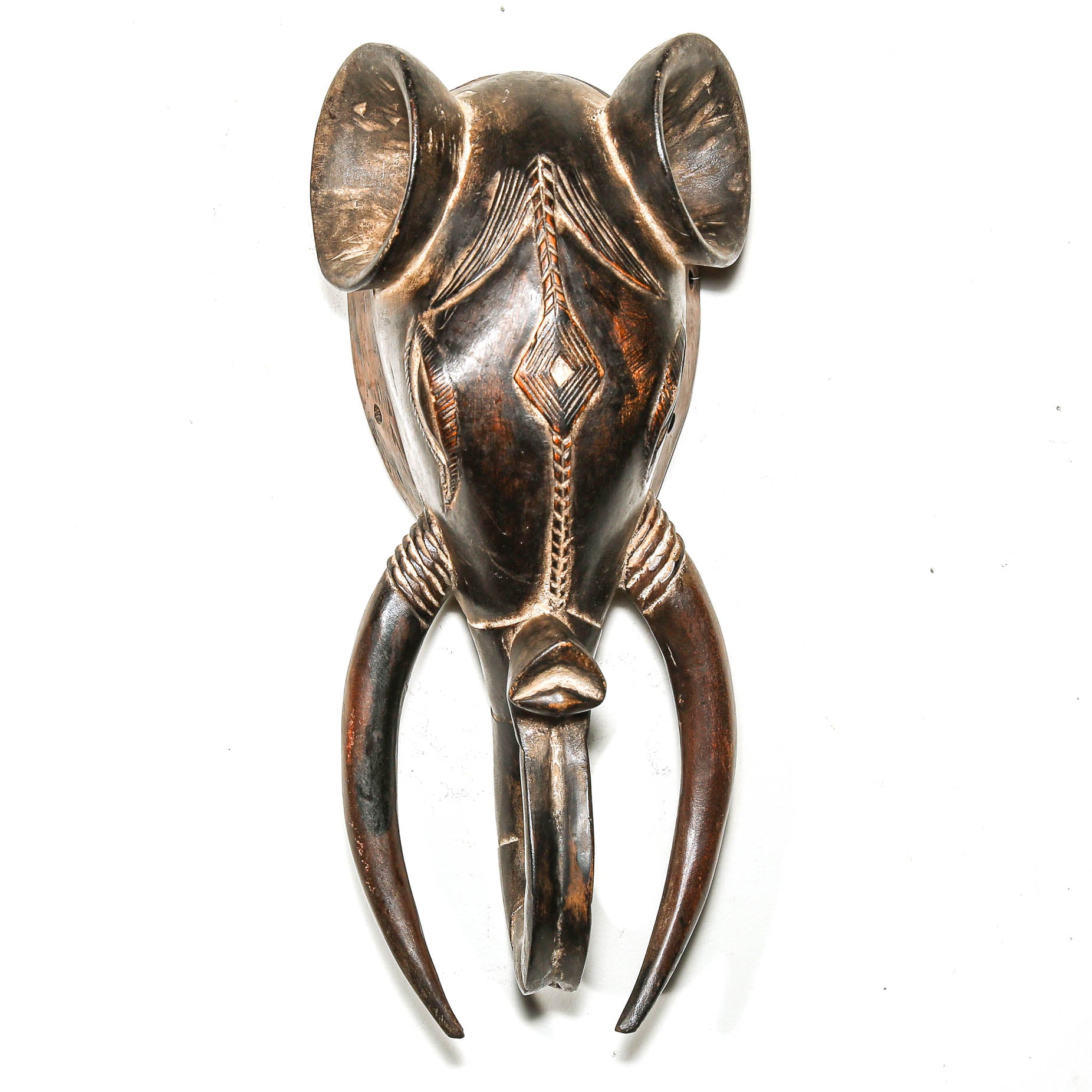 Decorative wooden African elephant head with intricate designs on a white background