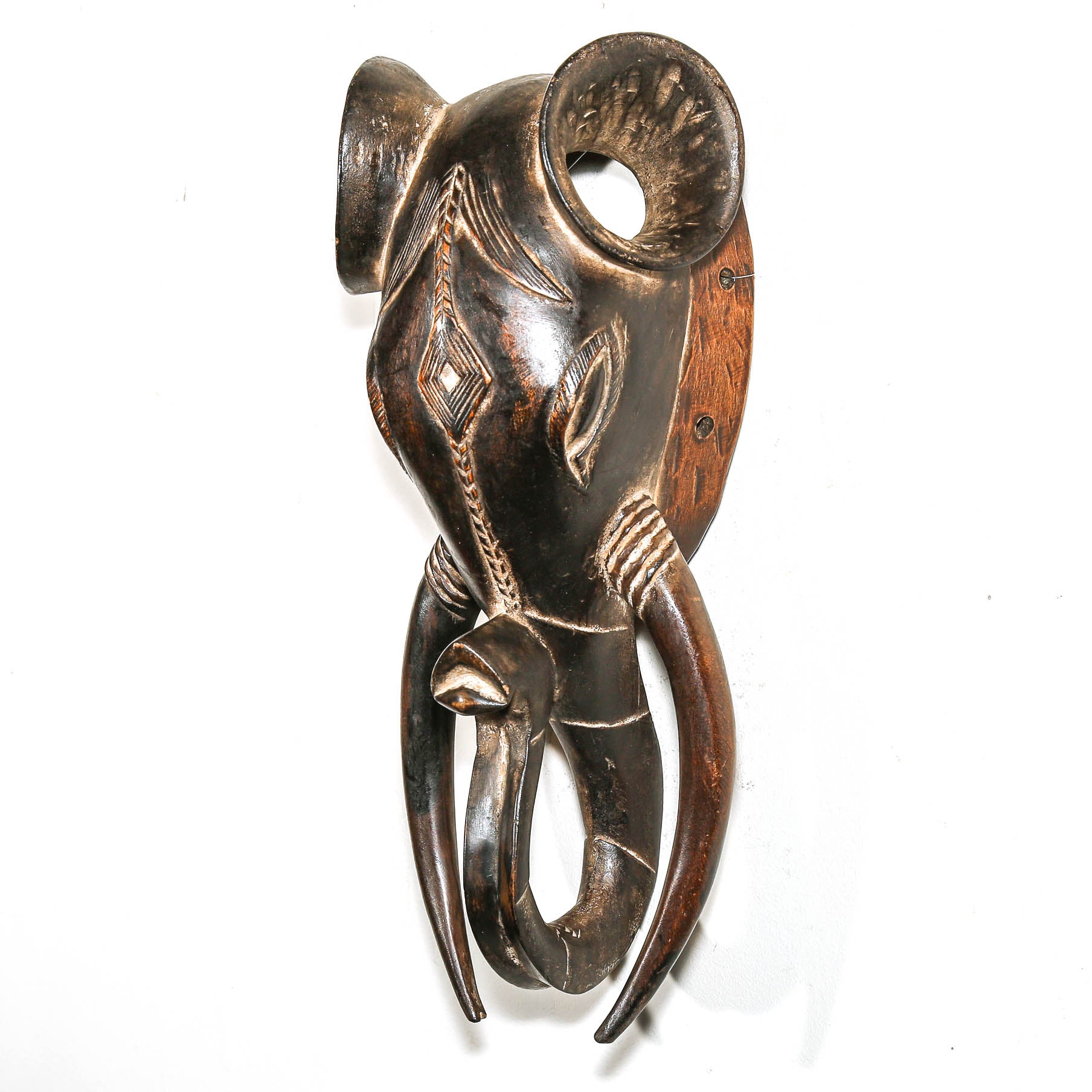 Decorative wooden elephant head mask with intricate carvings on a white background