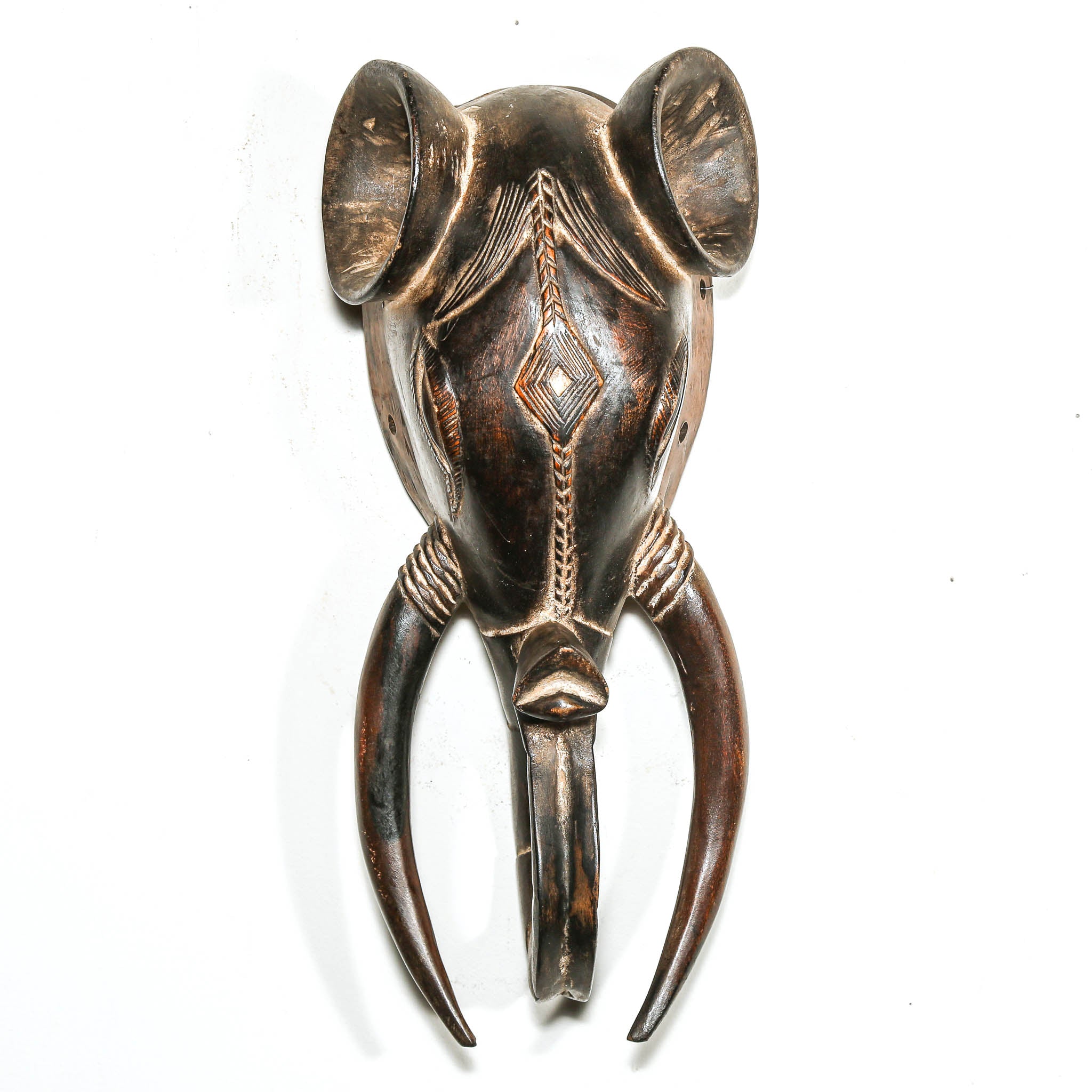 Decorative metal elephant head with intricate designs on a white background