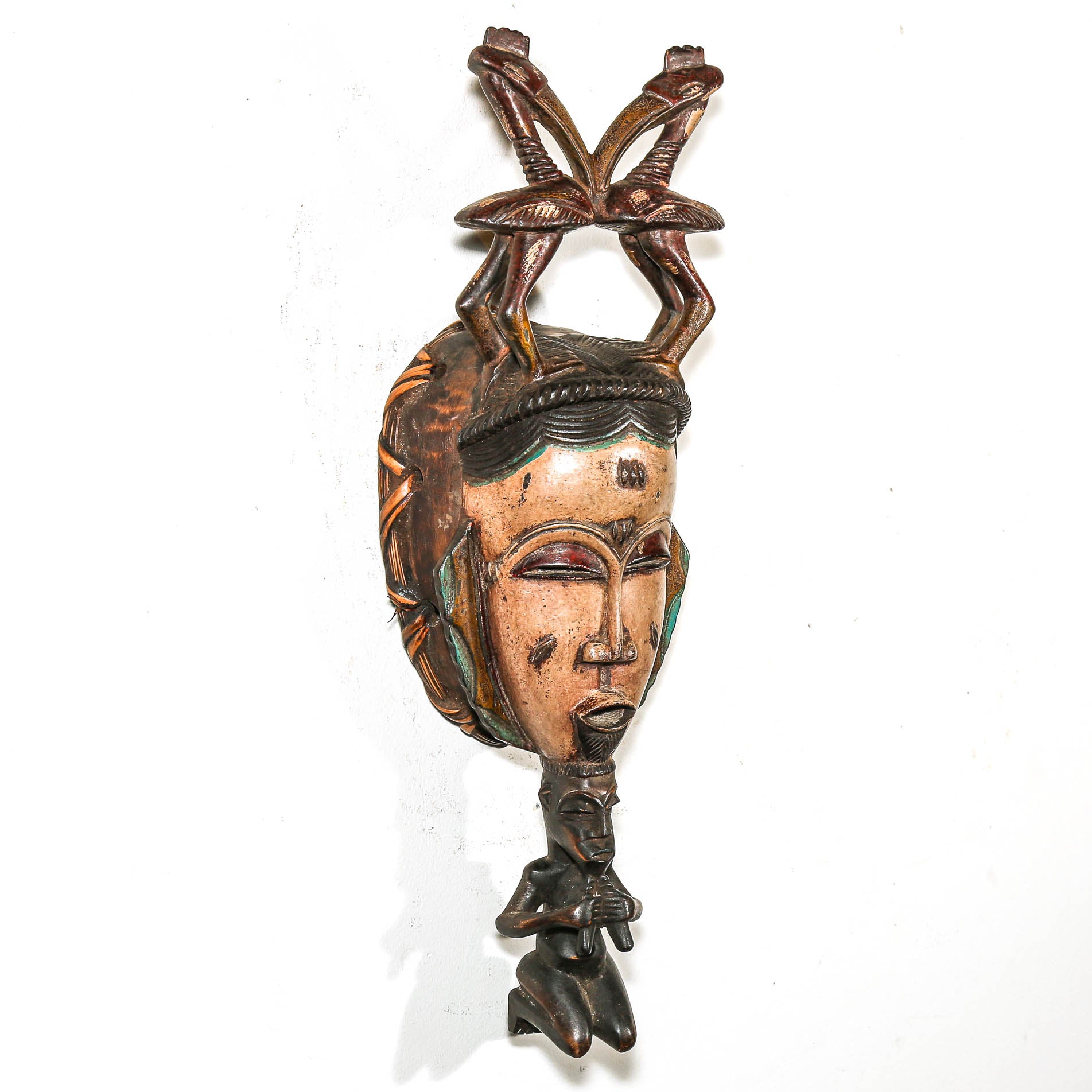 Carved wooden mask with intricate details on a white background