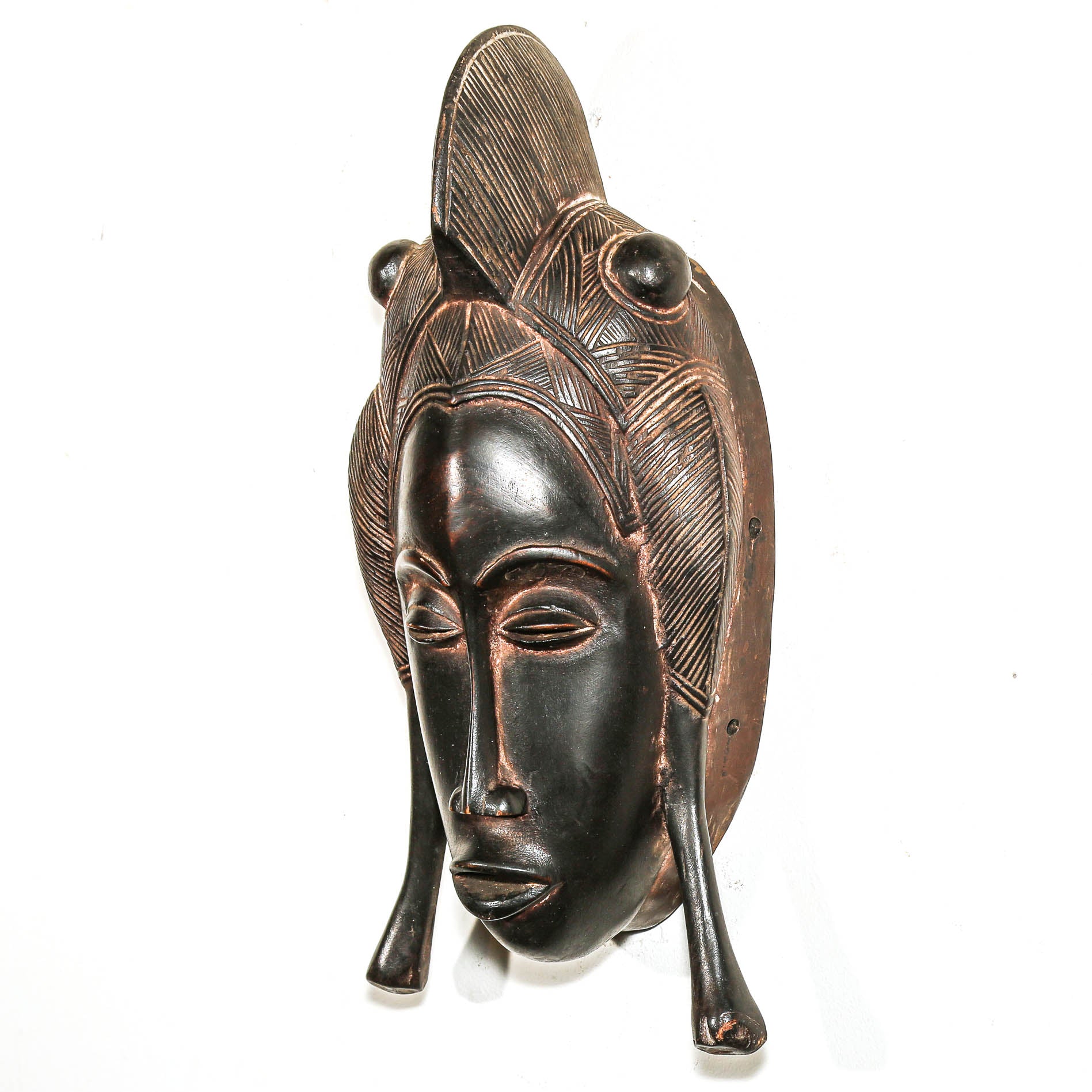 Wood mask with detailed facial features and feather-like extensions on a white background