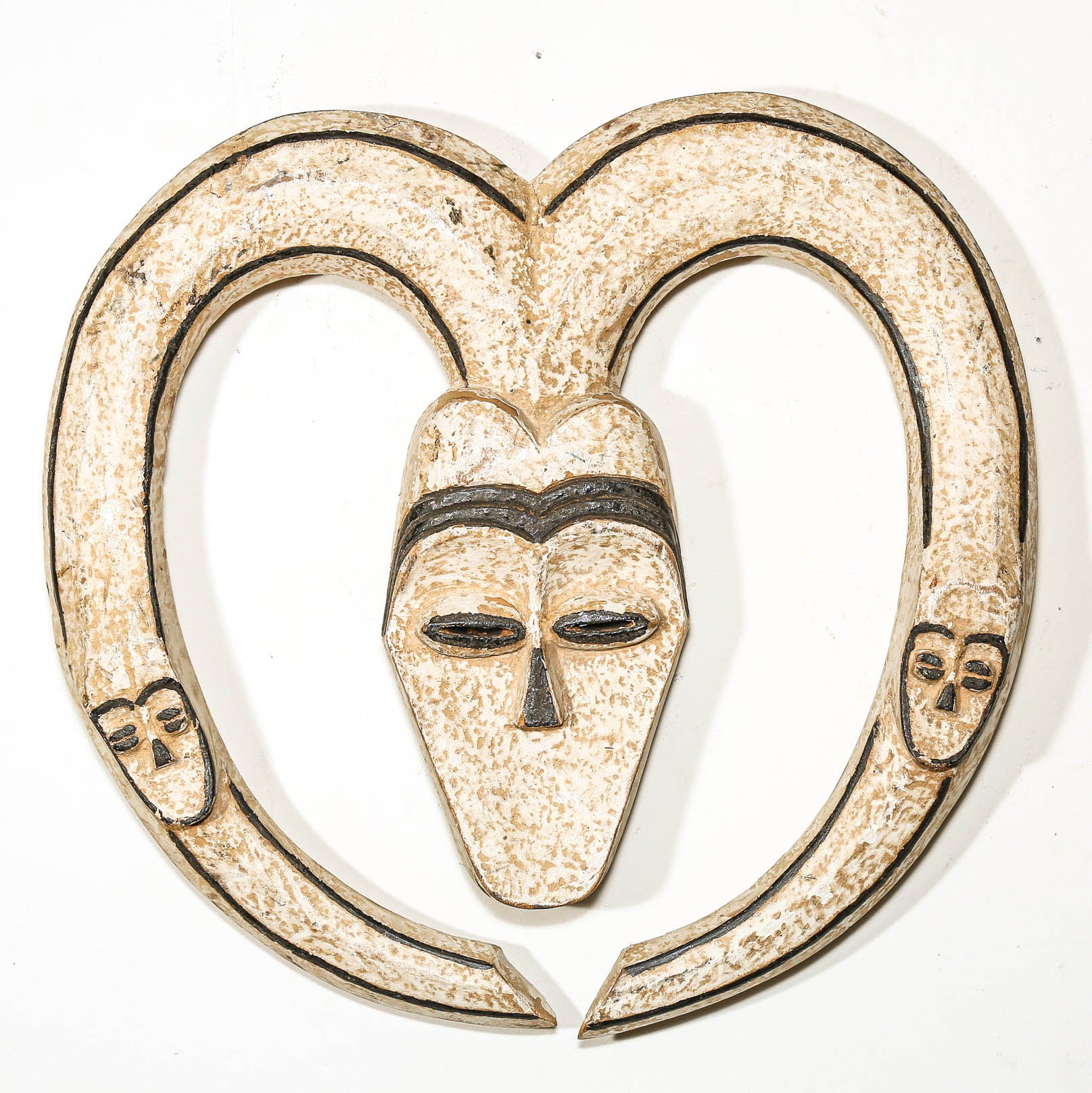Decorative wall hanging African mask with a heart shape and black lines on a white background