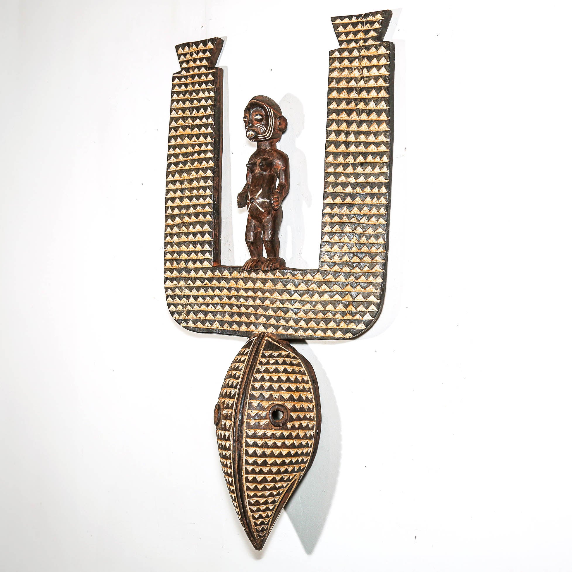 Decorative black and white wall piece with geometric patterns and a central figure on a white background