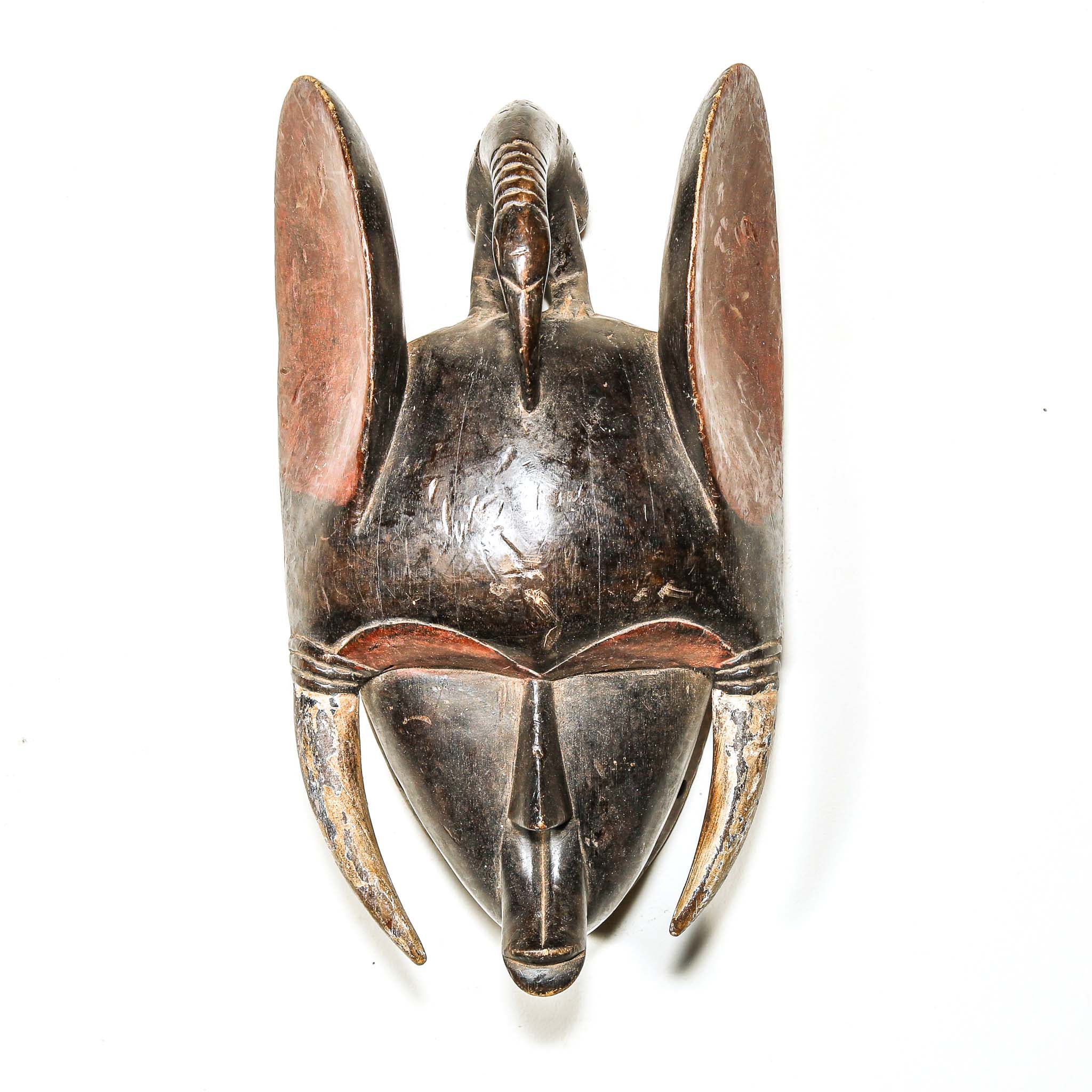 Wooden black art mask with elephant ears and tusks on a white background from Africa