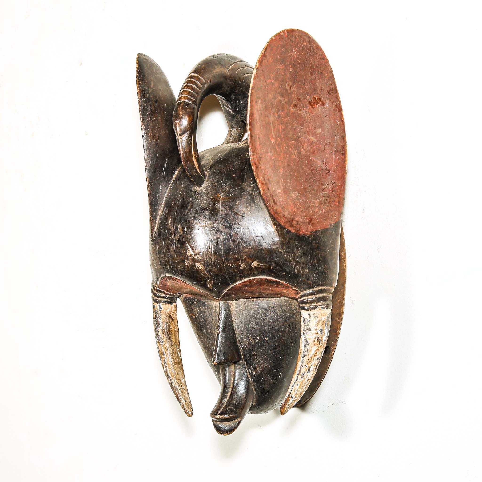 Wooden black art mask with elephant ears and tusks on a white background from Africa
