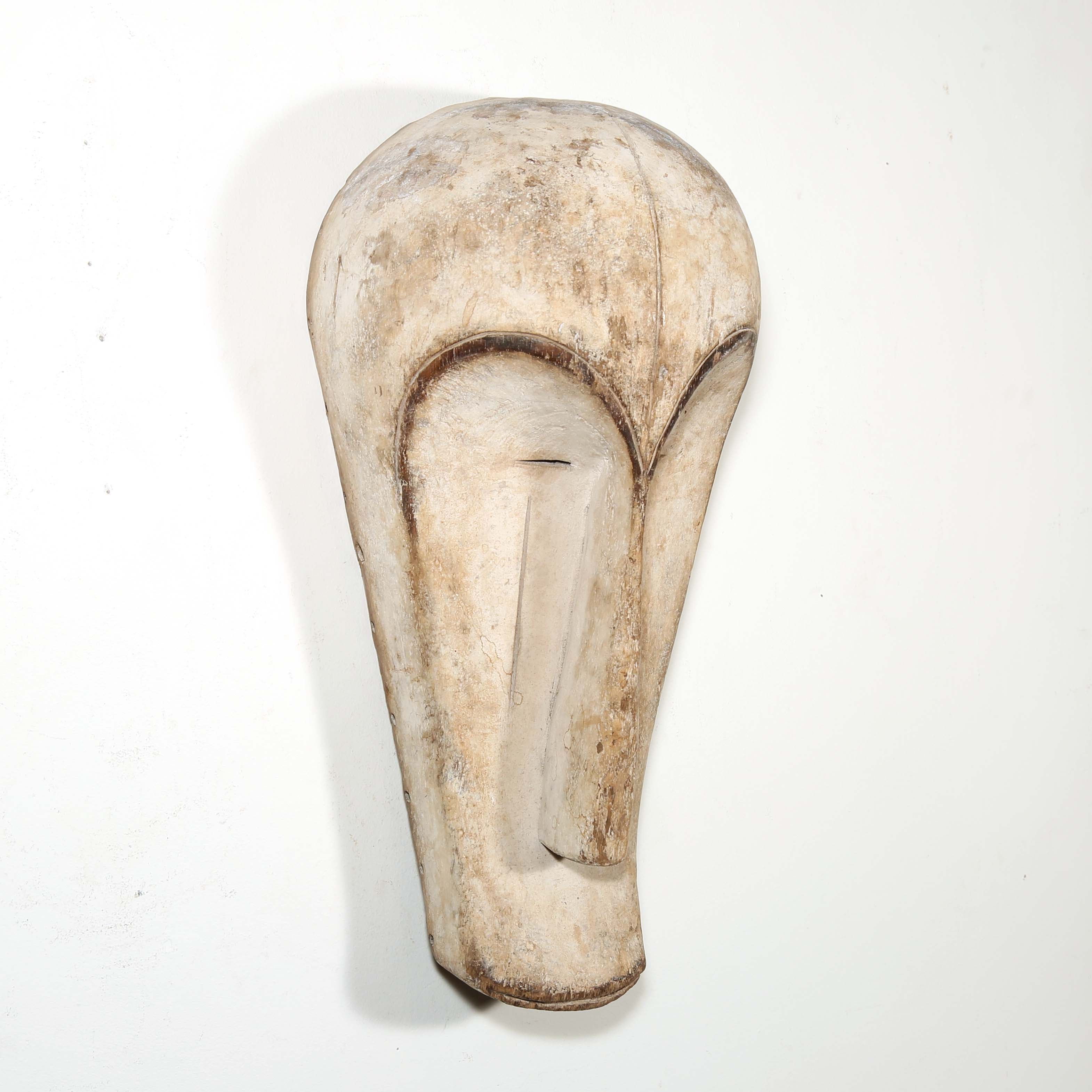 Authentic African mask to purchase online with neutral color designs hanging on a white wall