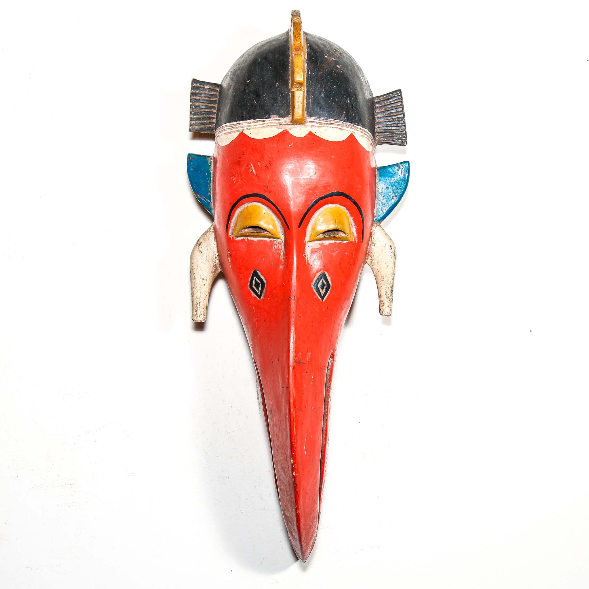 Colorful wooden mask with red face and black and blue accents on a white background tribal African interior design