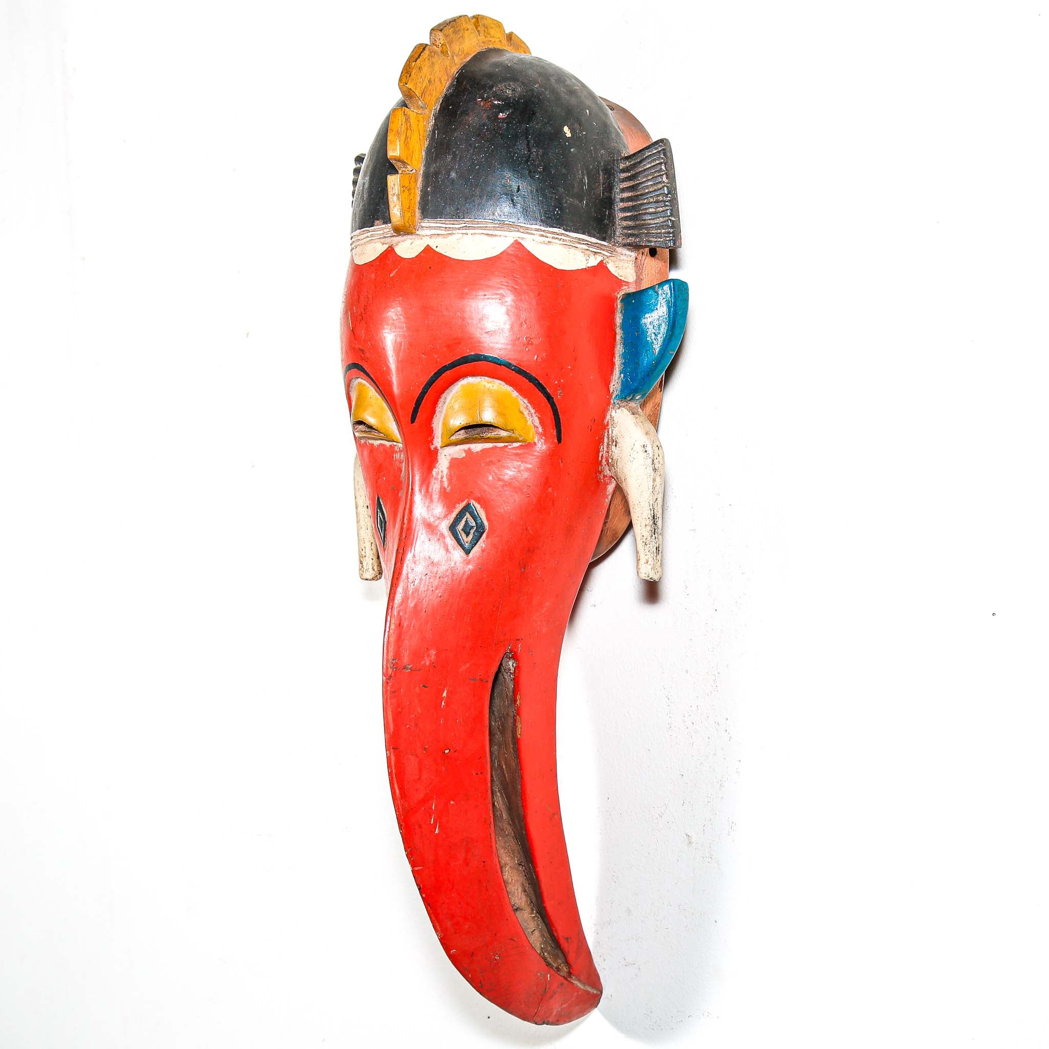 Colorful African wooden mask with a long red bird face on a white background