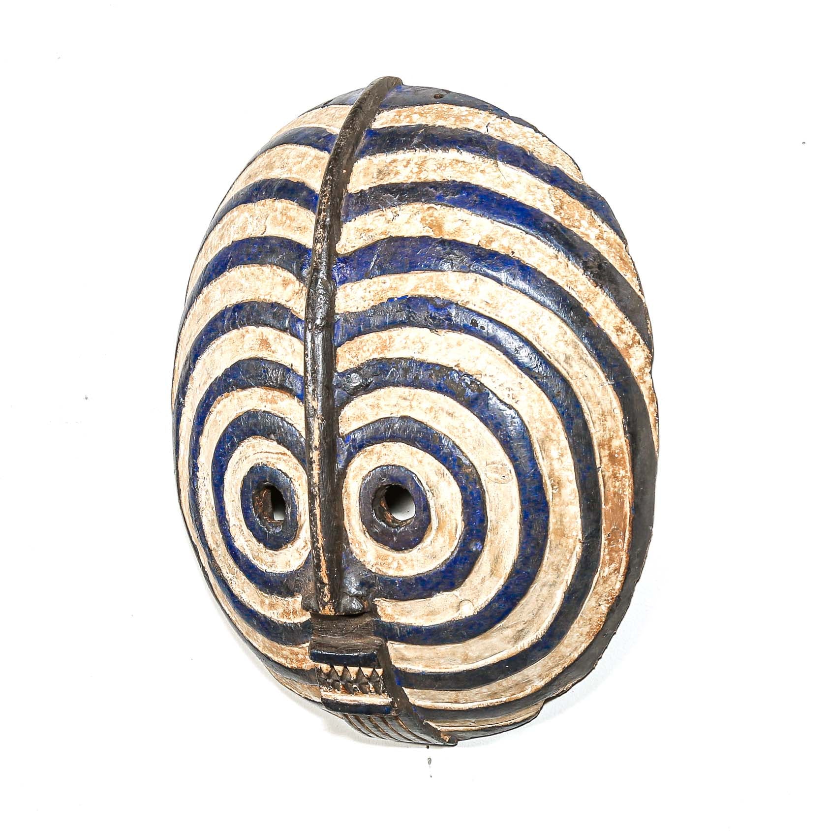 wood mask in the shape of a  face with blue and beige spiral patterns on a white background