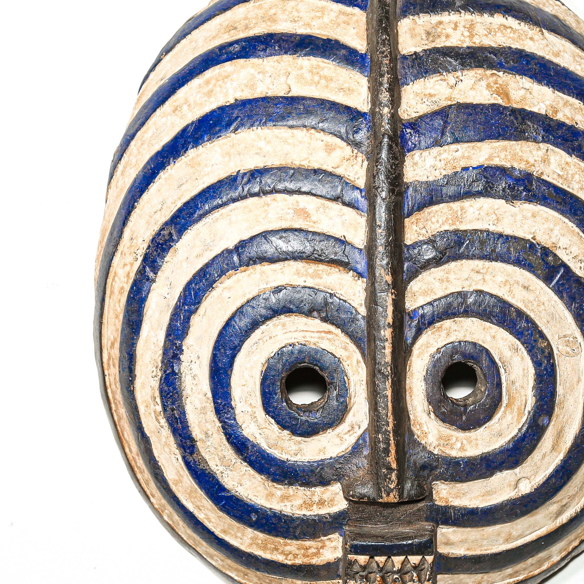 round Decorative African mask with blue and beige concentric circles on a white background