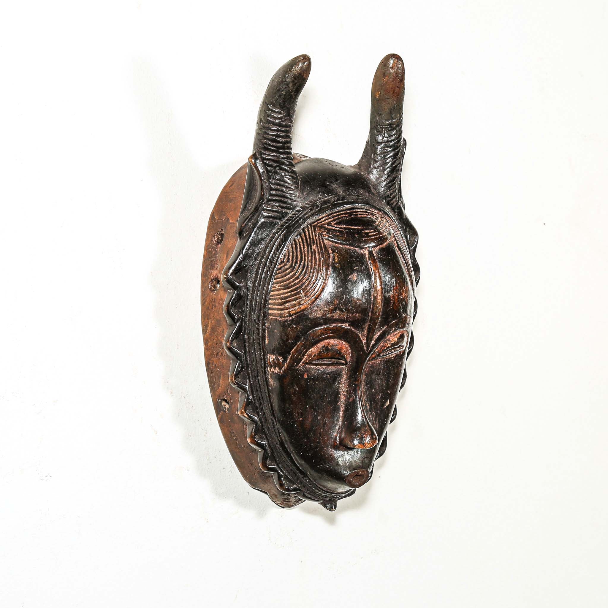 brown and black African mask with horns on a white background