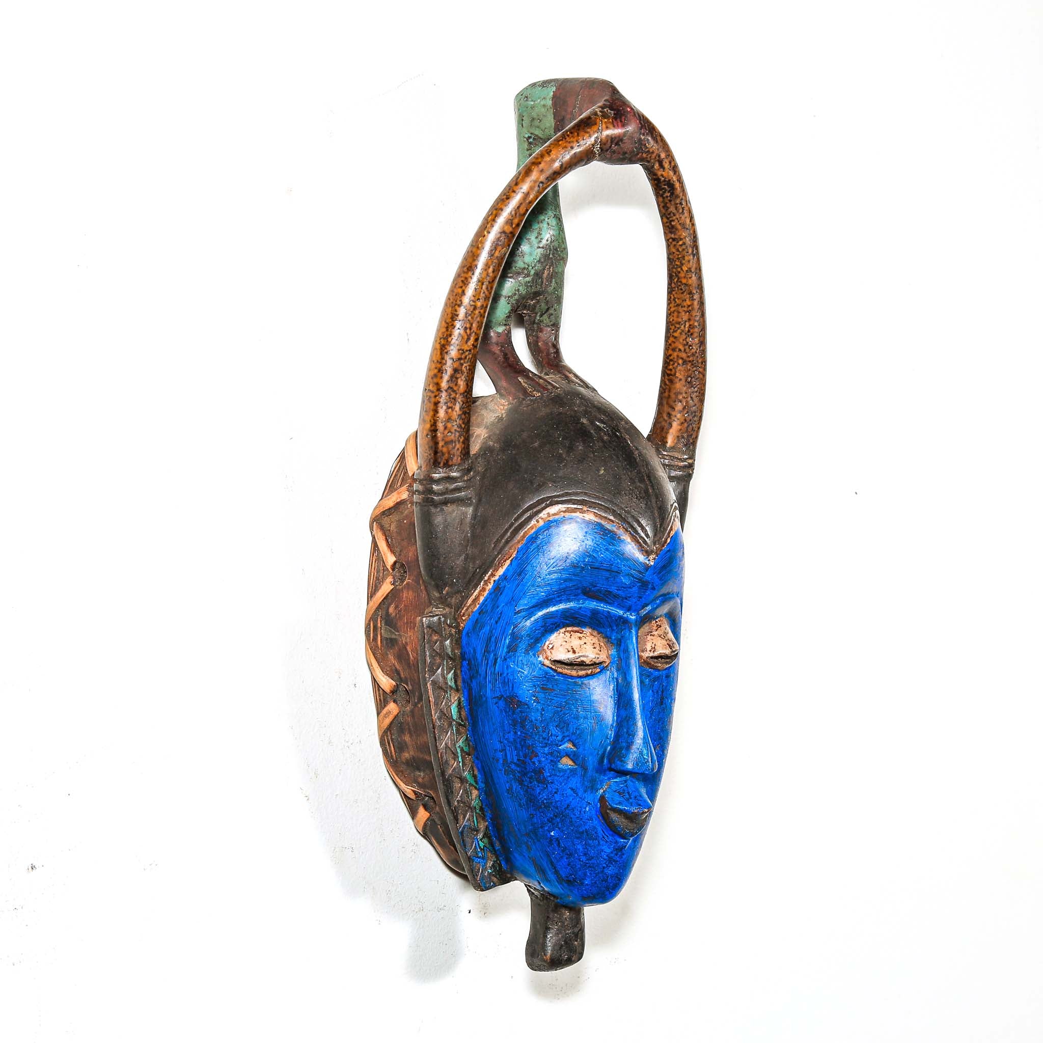 Decorative wooden African mask with blue face and brown arch on a white background authentic art and artist from Africa