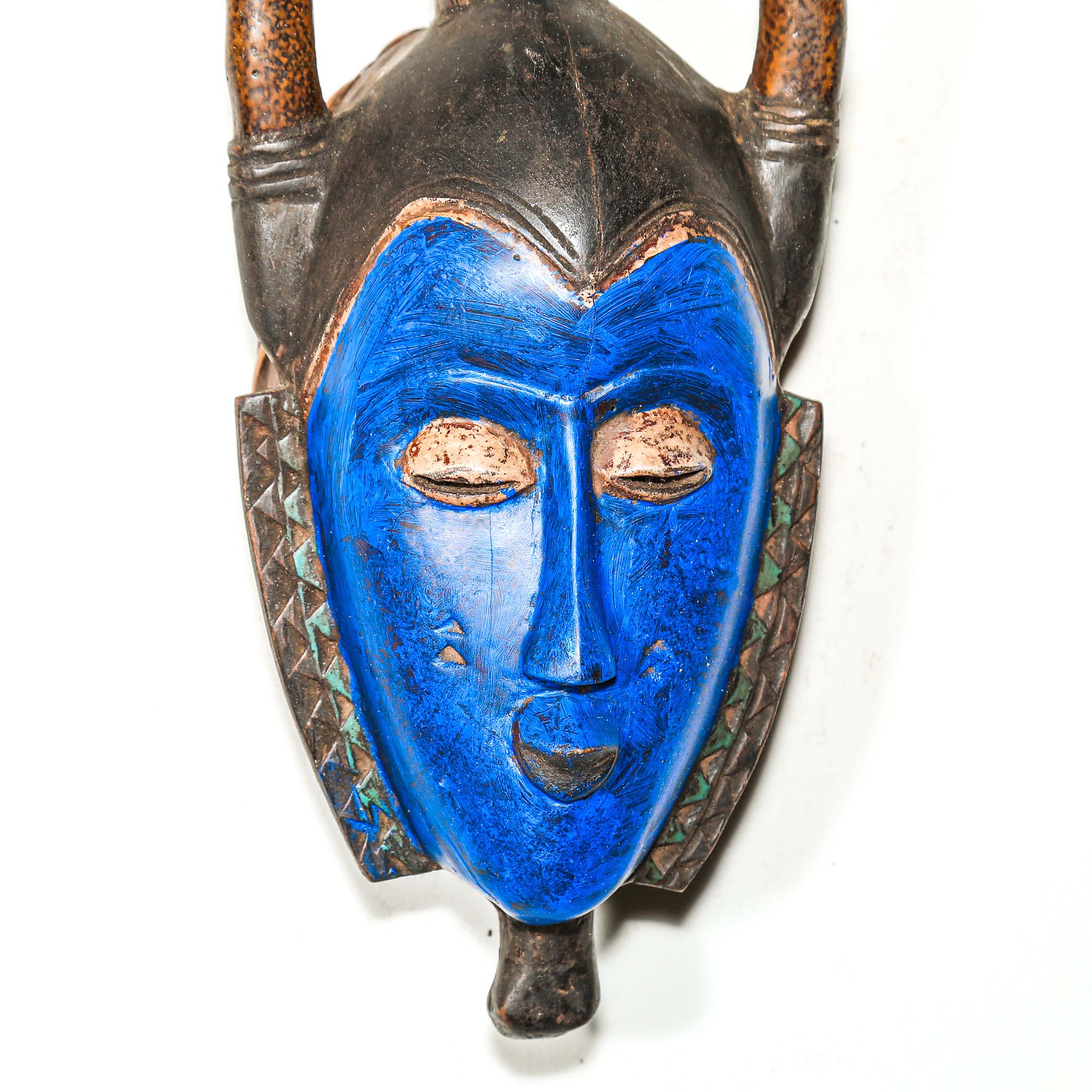 Decorative wooden African mask with blue face and brown arch on a white background authentic art and artist from Africa