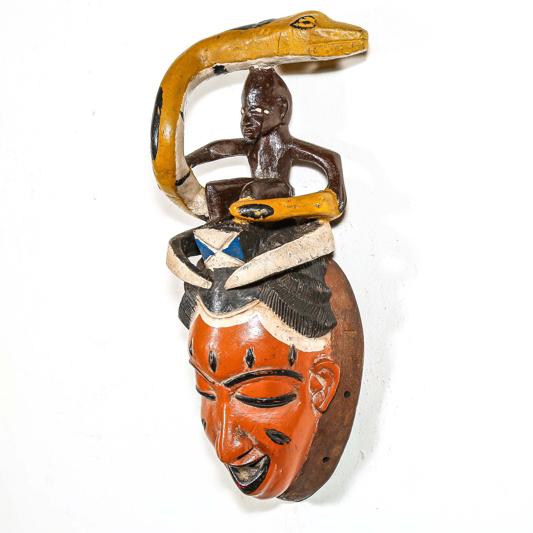 Decorative mask with a snake coiled around a figure from Africa on a white background
