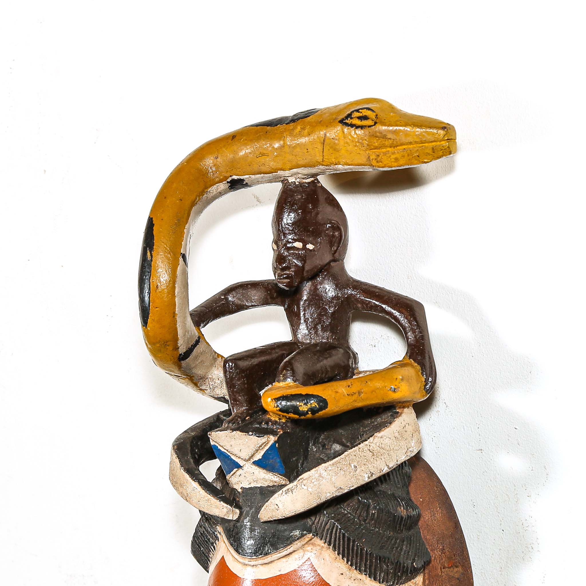 Decorative mask with a snake coiled around a figure from Africa on a white background