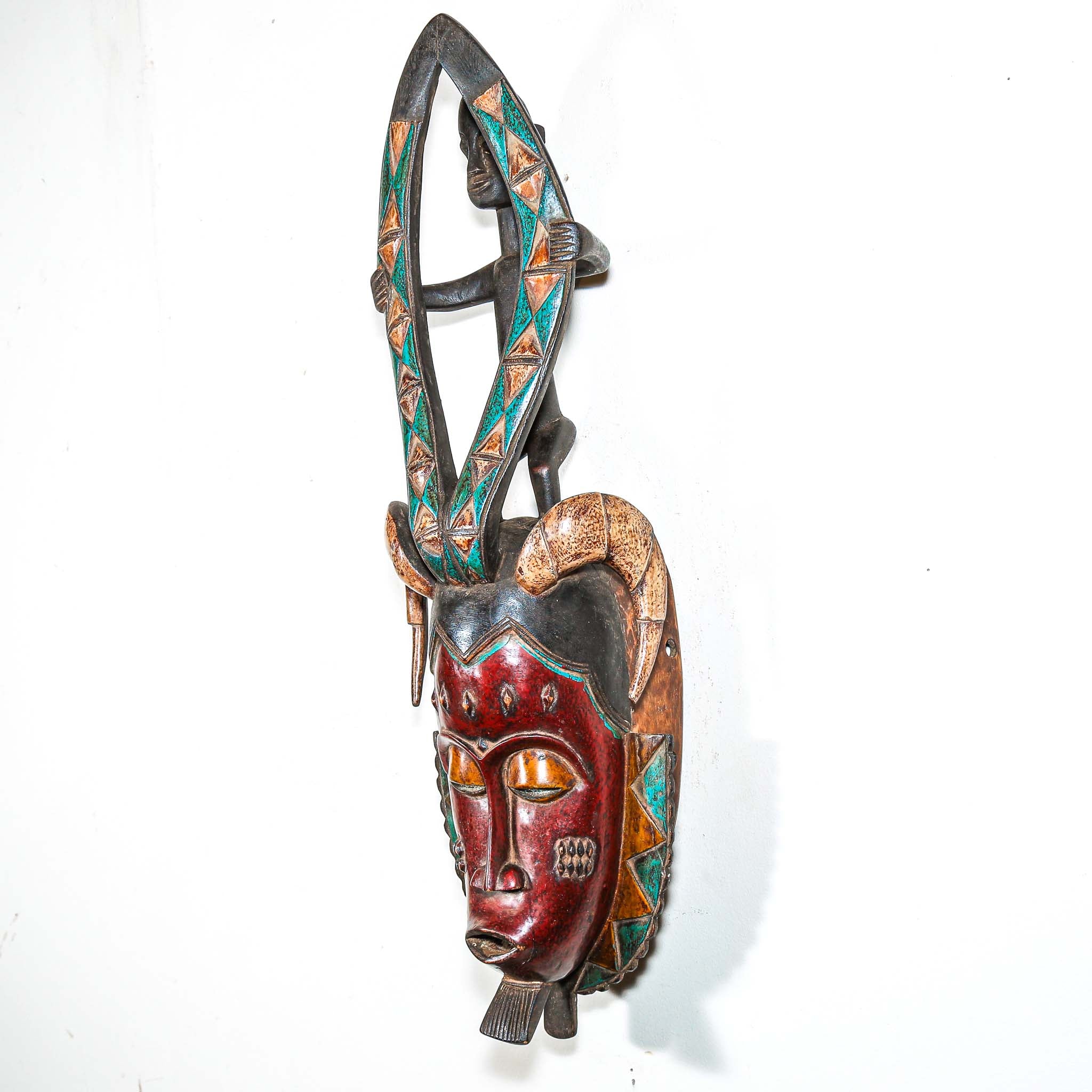 Decorative hand made wooden mask by an African artist with intricate designs on a white background