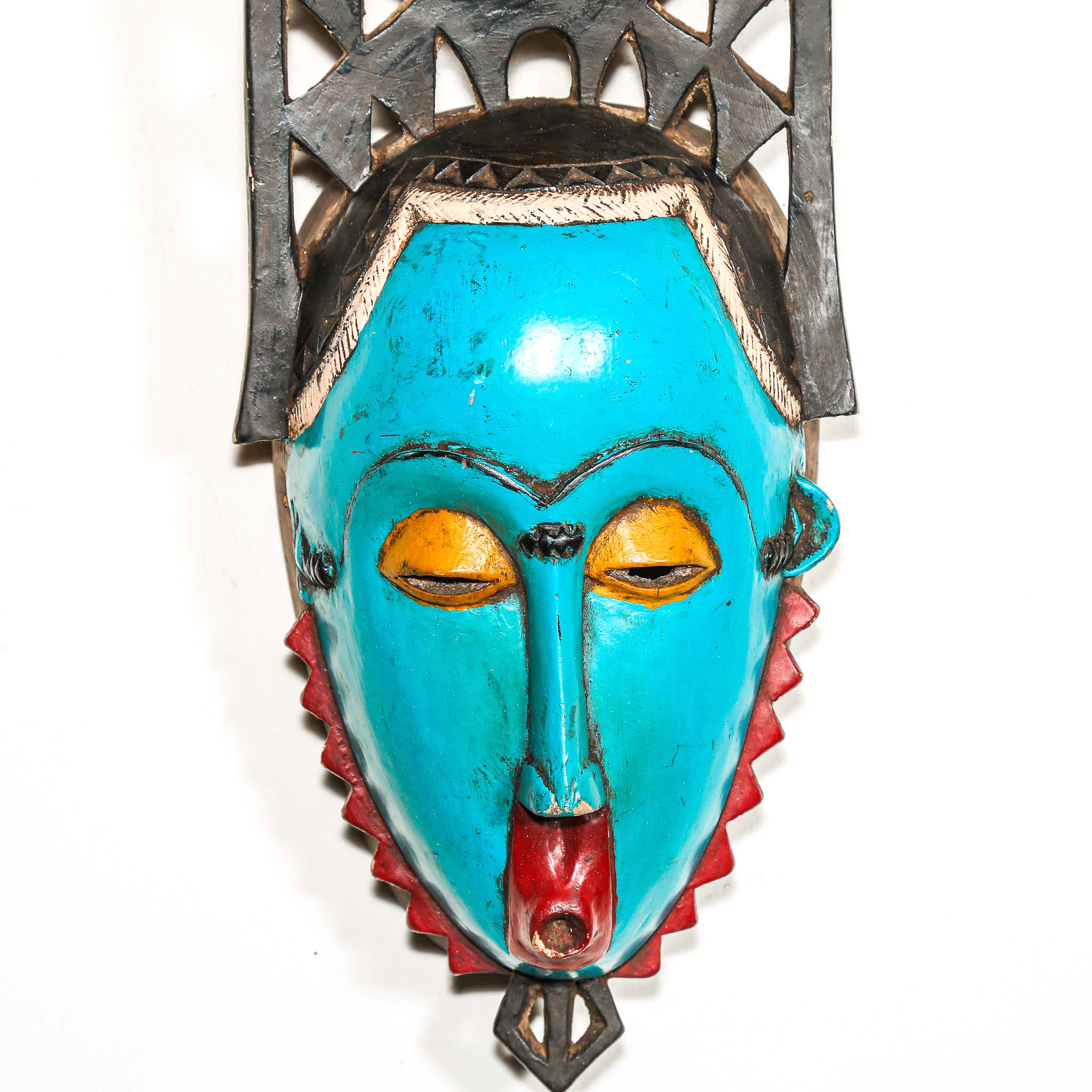 Colorful African wall mask with turquoise face, red and yellow accents on a white background