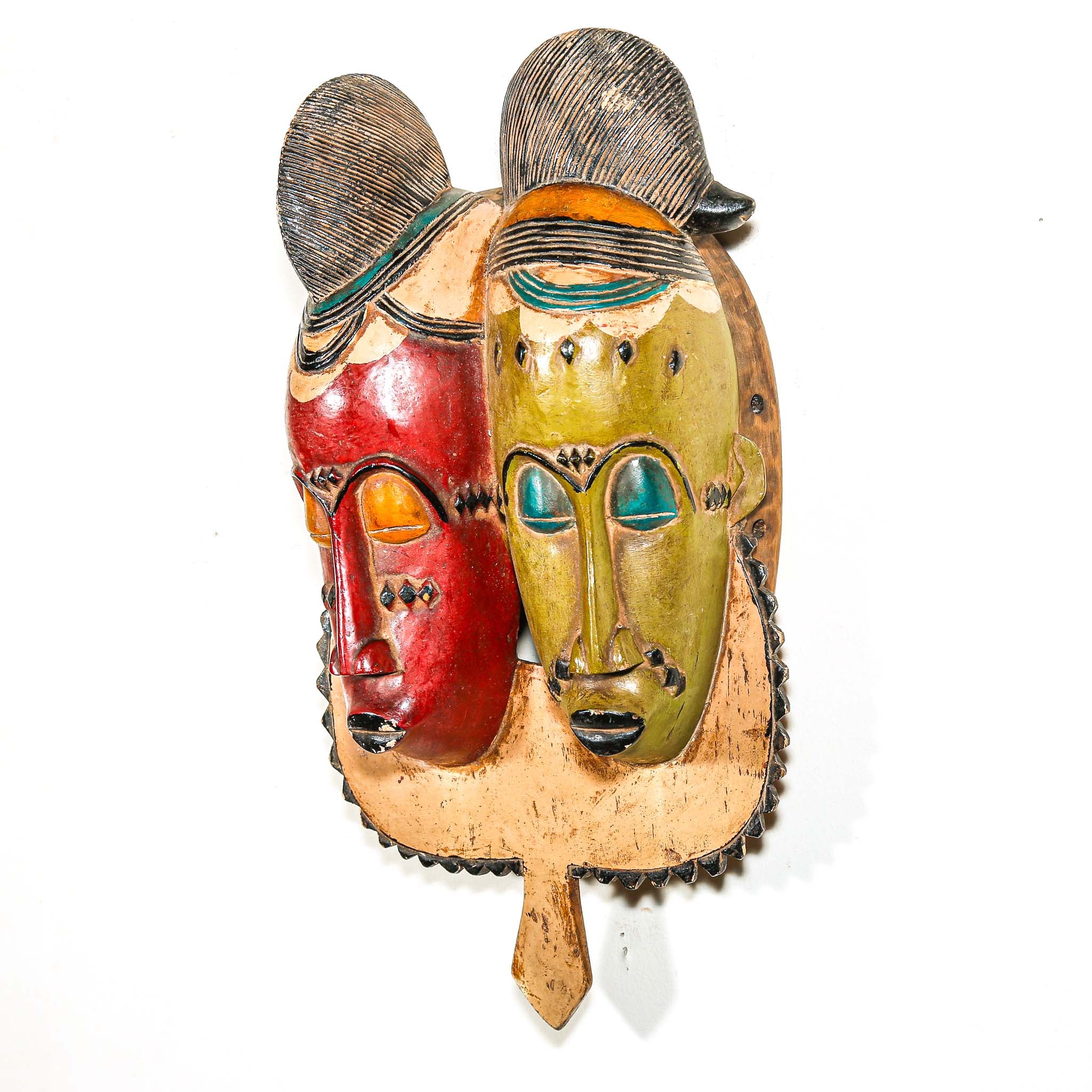 brightly colored African wooden mask with two faces on a white background