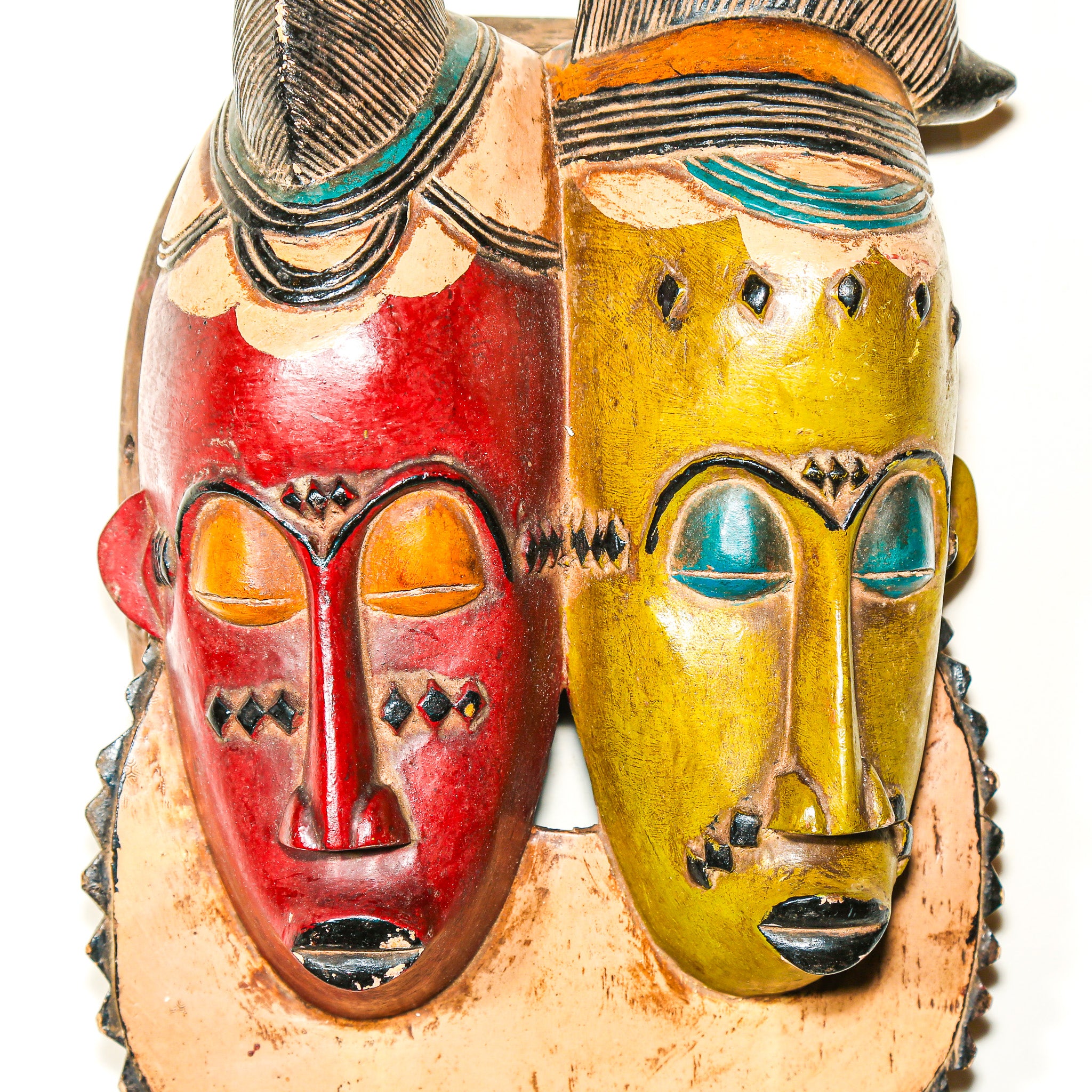brightly colored African wooden mask with two faces on a white background