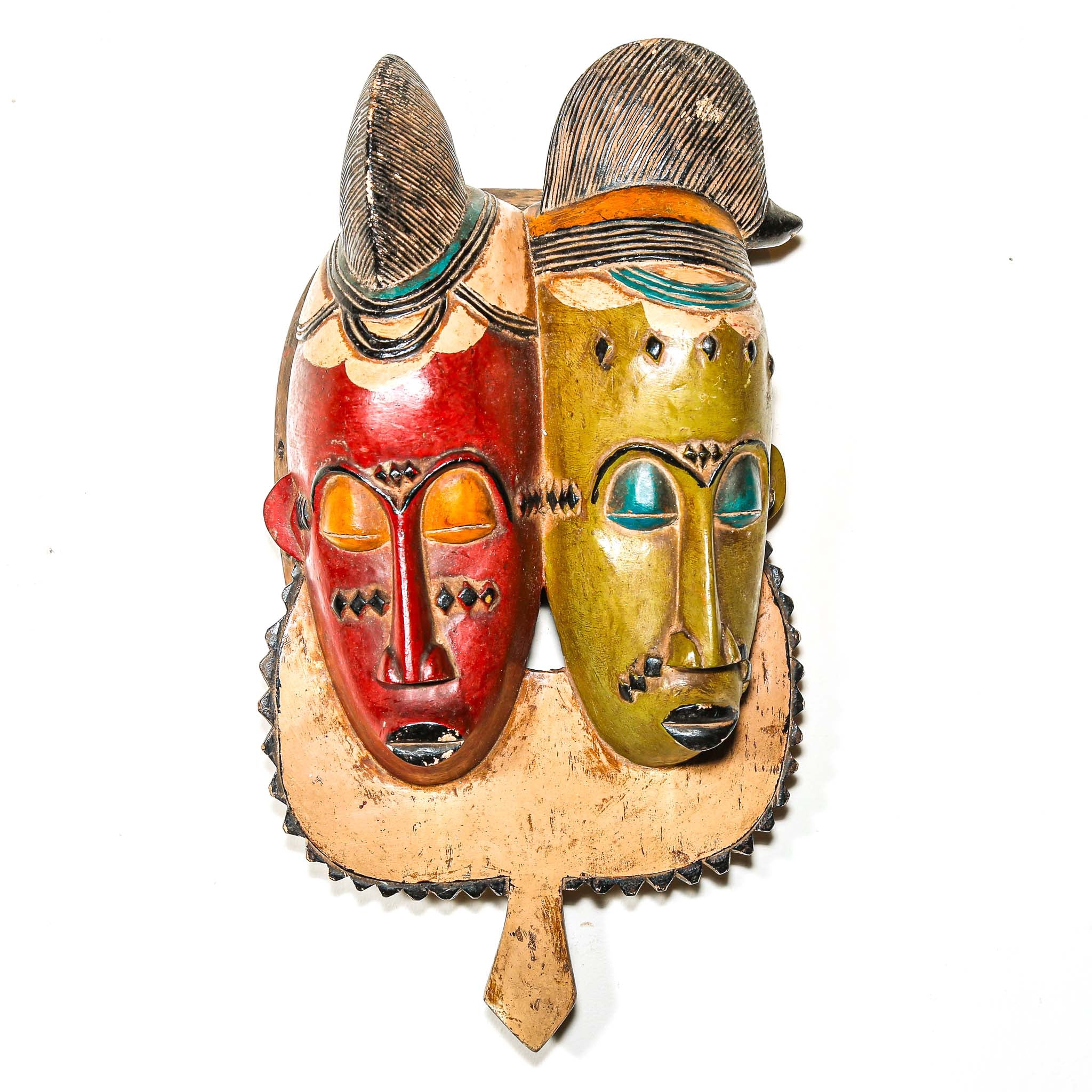 brightly colored African wooden mask with two faces on a white background