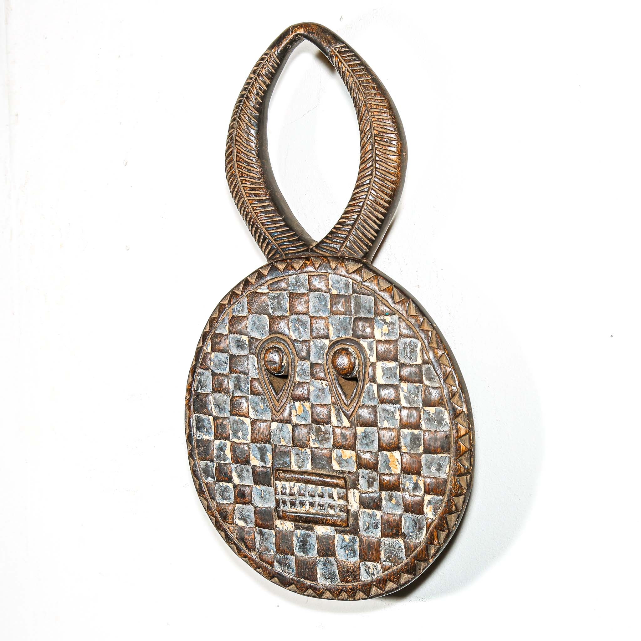 Decorative wooden traditional african mask with checkered pattern and eye design and horns on a white background