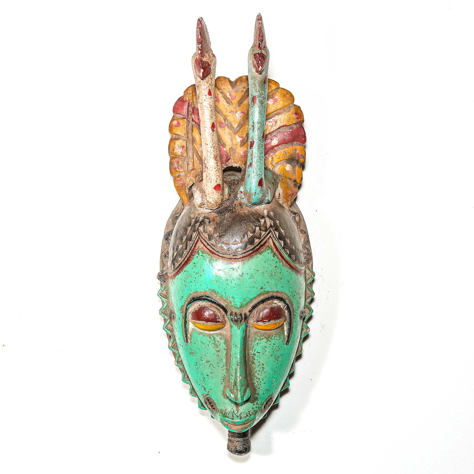 Tribal African mask with green face and colorful headdress with two birds on a white background