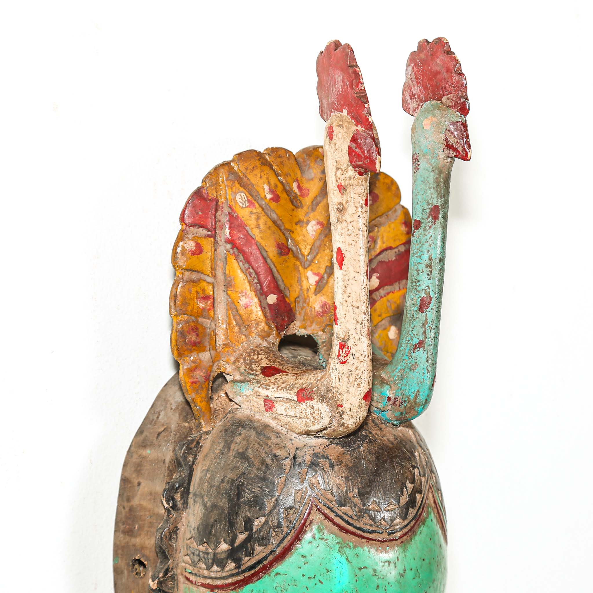 Tribal African mask with green face and colorful headdress with two birds on a white background