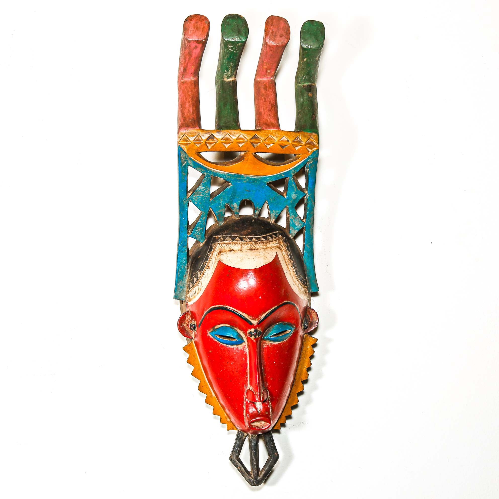 authentic tribal ceremonial red mask from Africa with colorful aesthetic displayed on a white wall