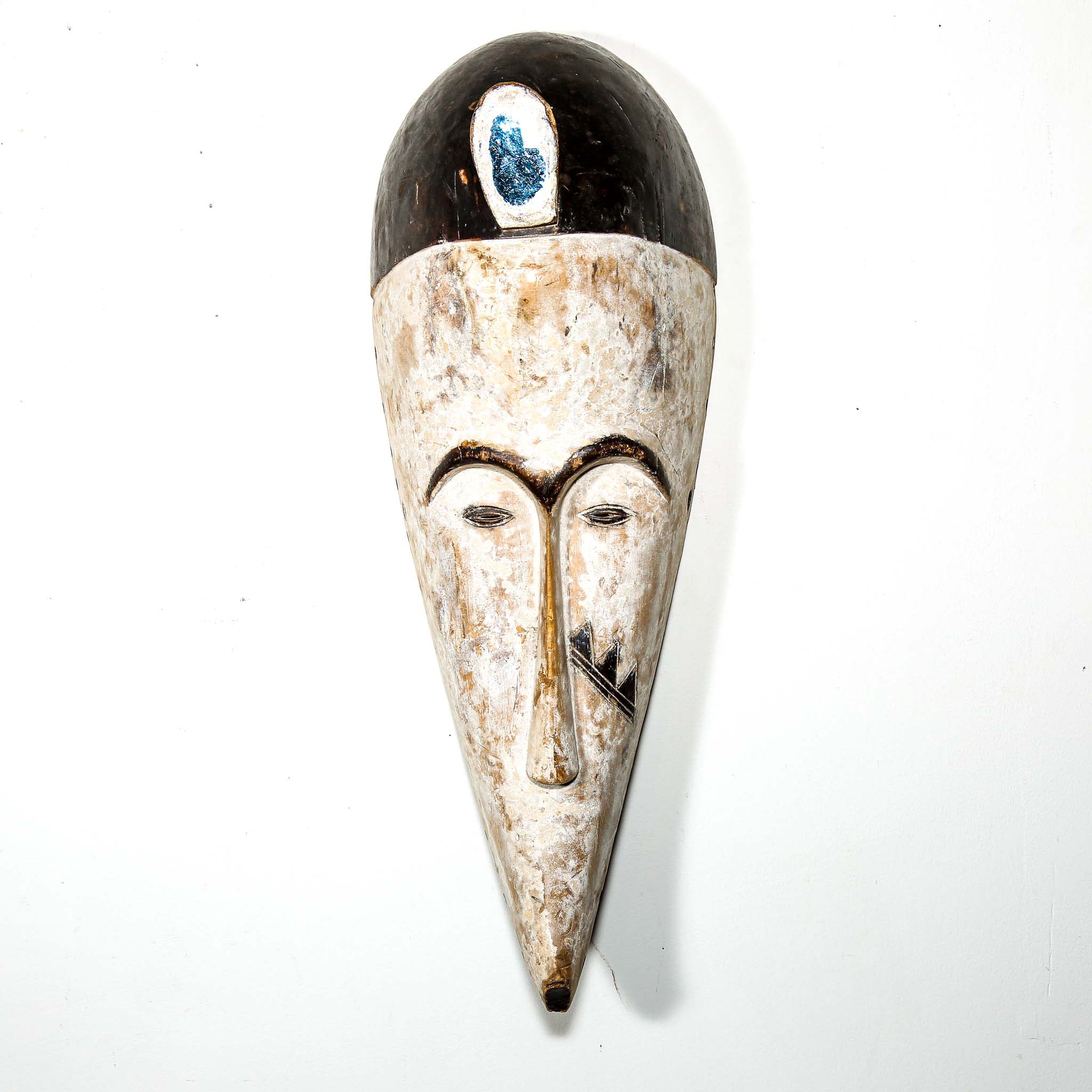 Authentic African mask to purchase online with neutral color designs hanging on a white wall