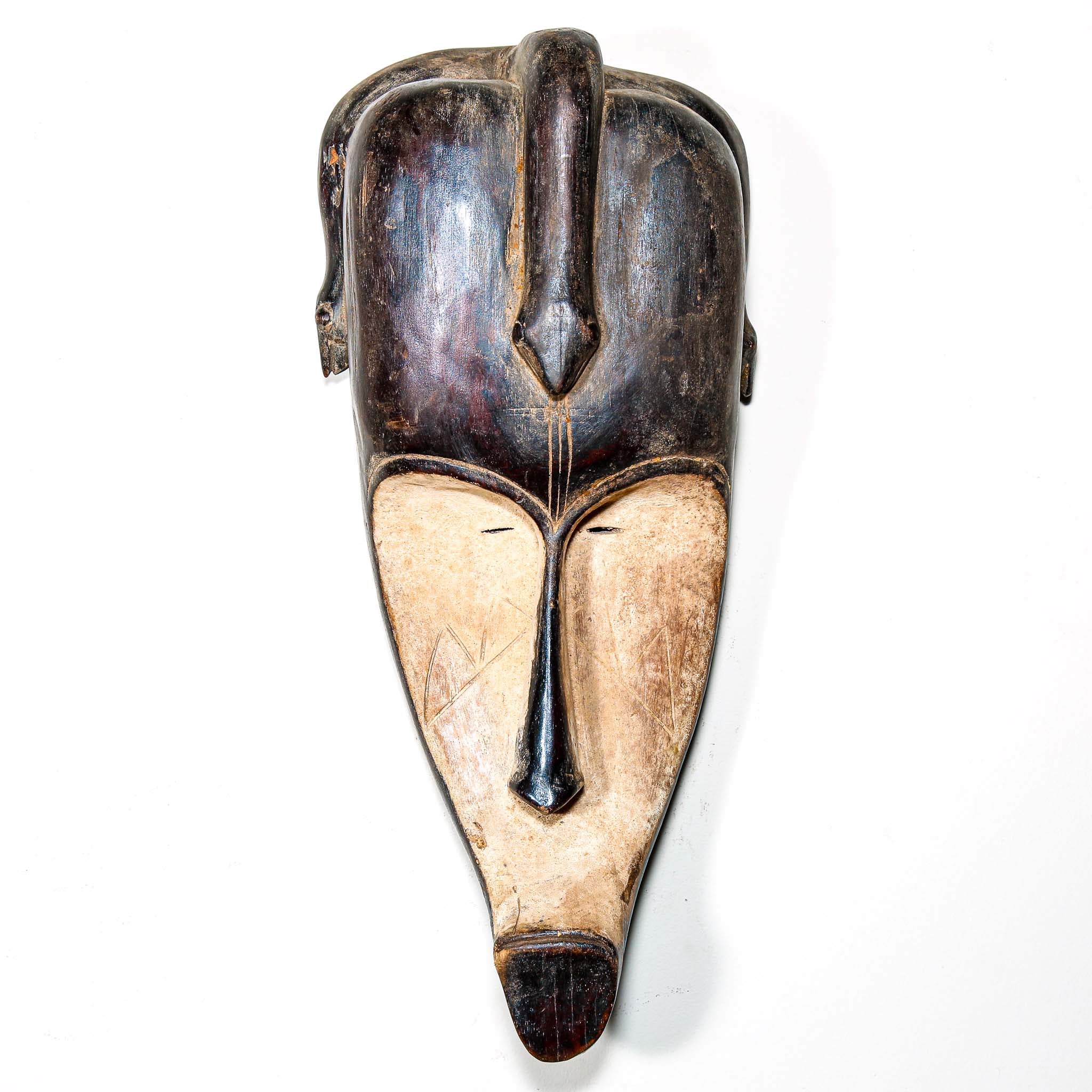Authentic African mask to purchase online with neutral color designs hanging on a white wall