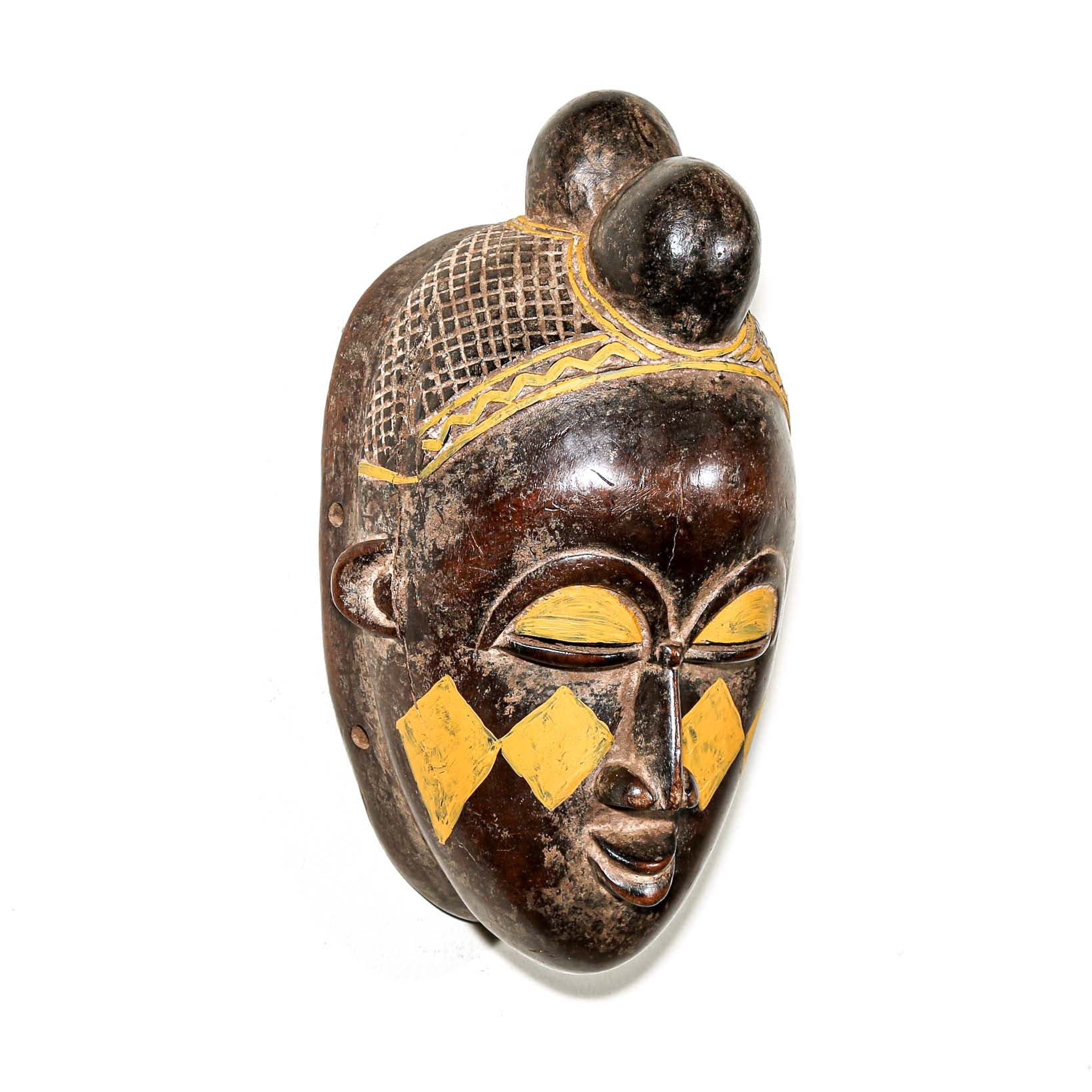 Wooden traditional African mask with yellow accents on a white background for sale