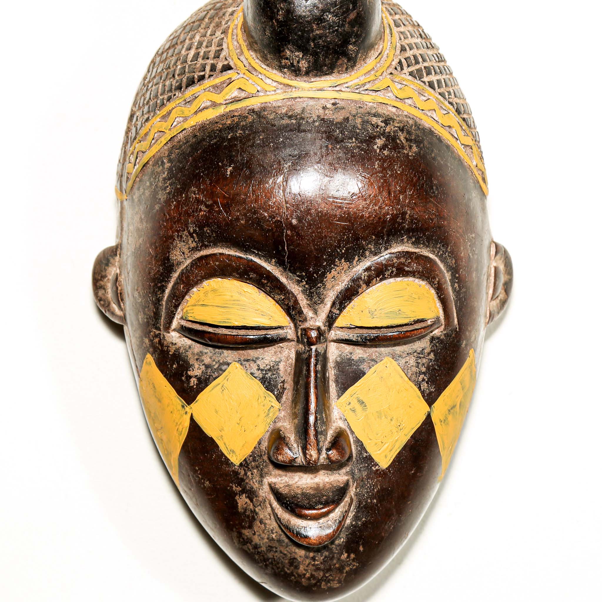 Wooden traditional African mask with yellow accents on a white background for sale