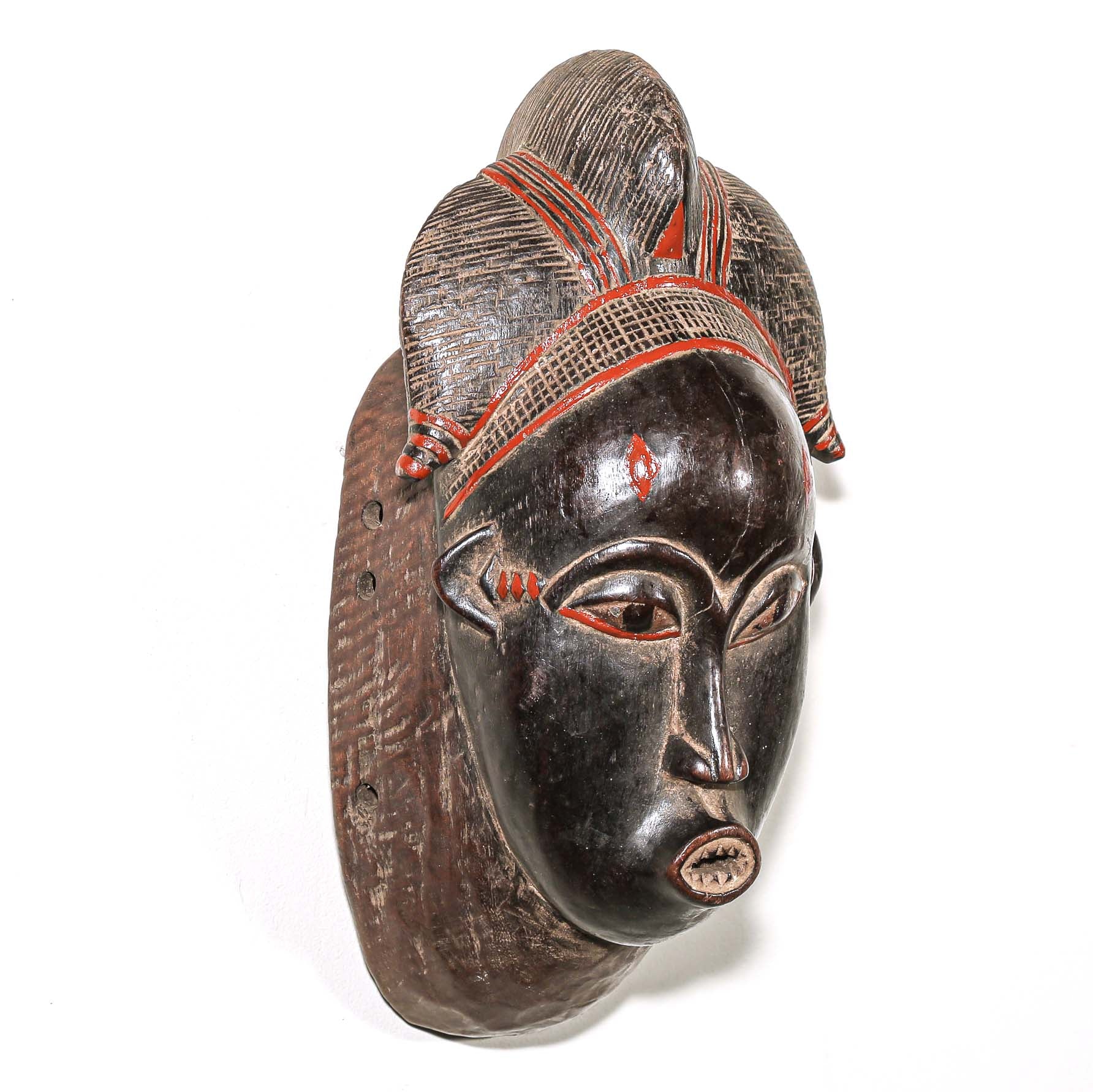 Wooden traditional African mask with black art face and red accents on a white background
