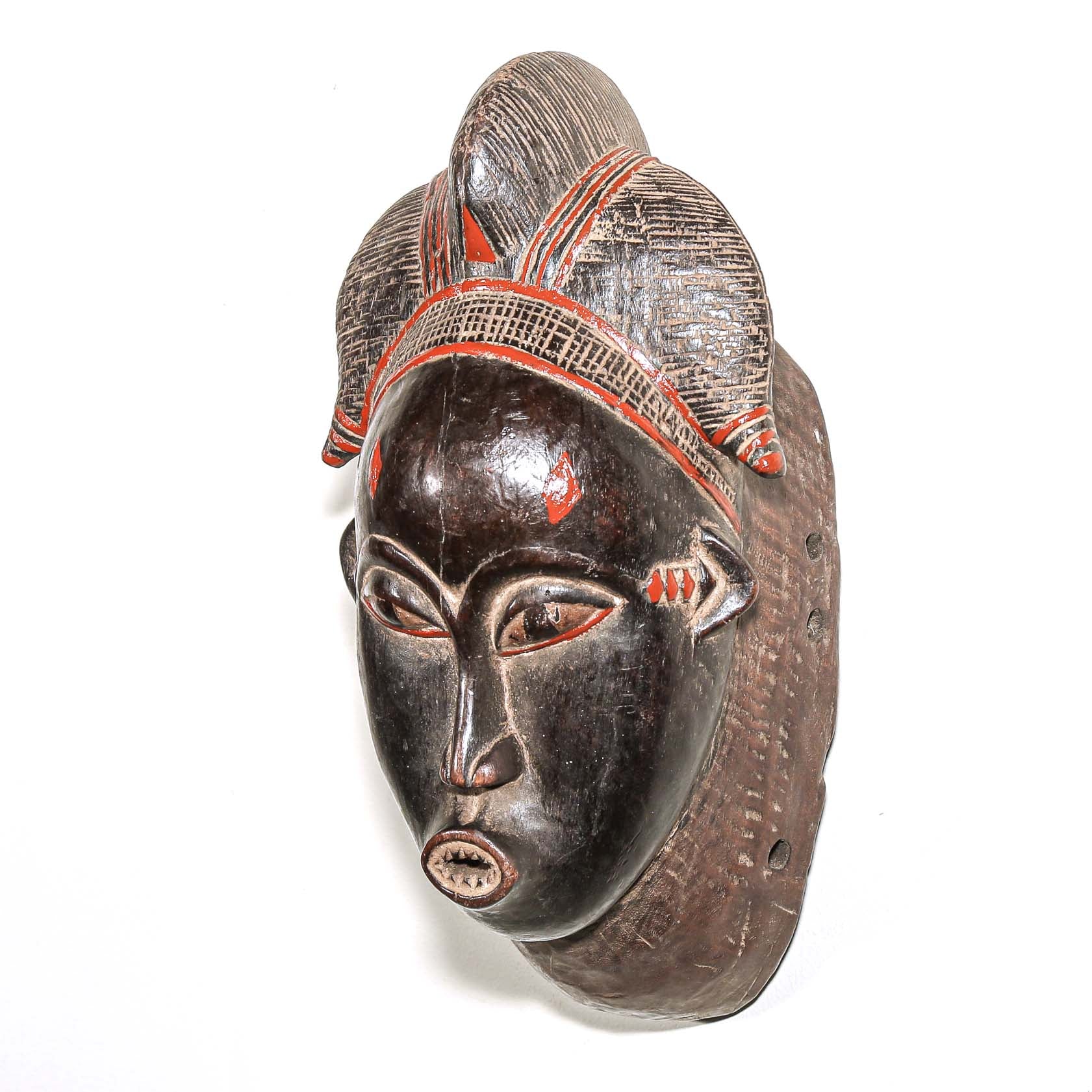 Wooden traditional African mask with black art face and red accents on a white background