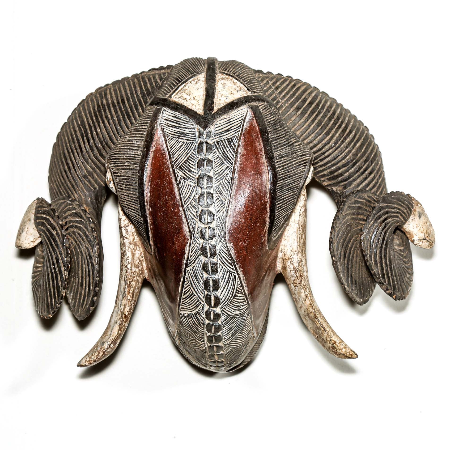 Decorative ram's head sculpture with intricate patterns on a white background from Africa