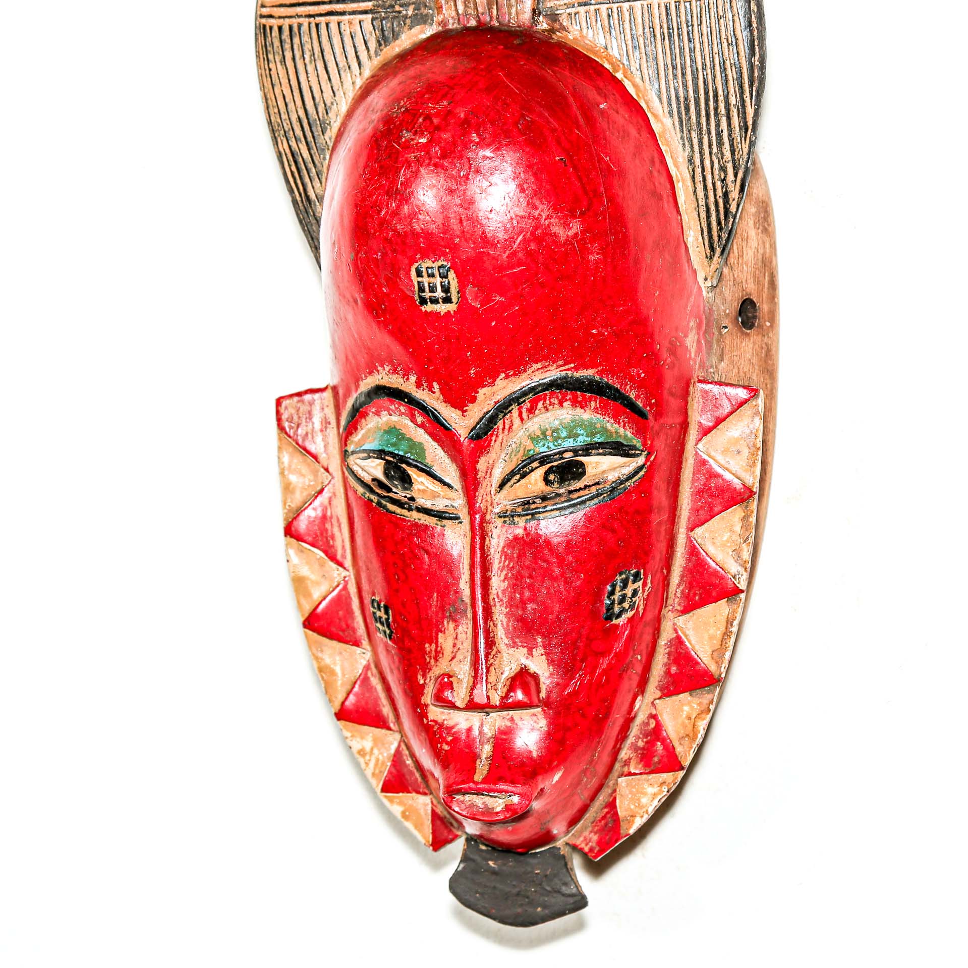 Red wooden mask with geometric patterns on a white background