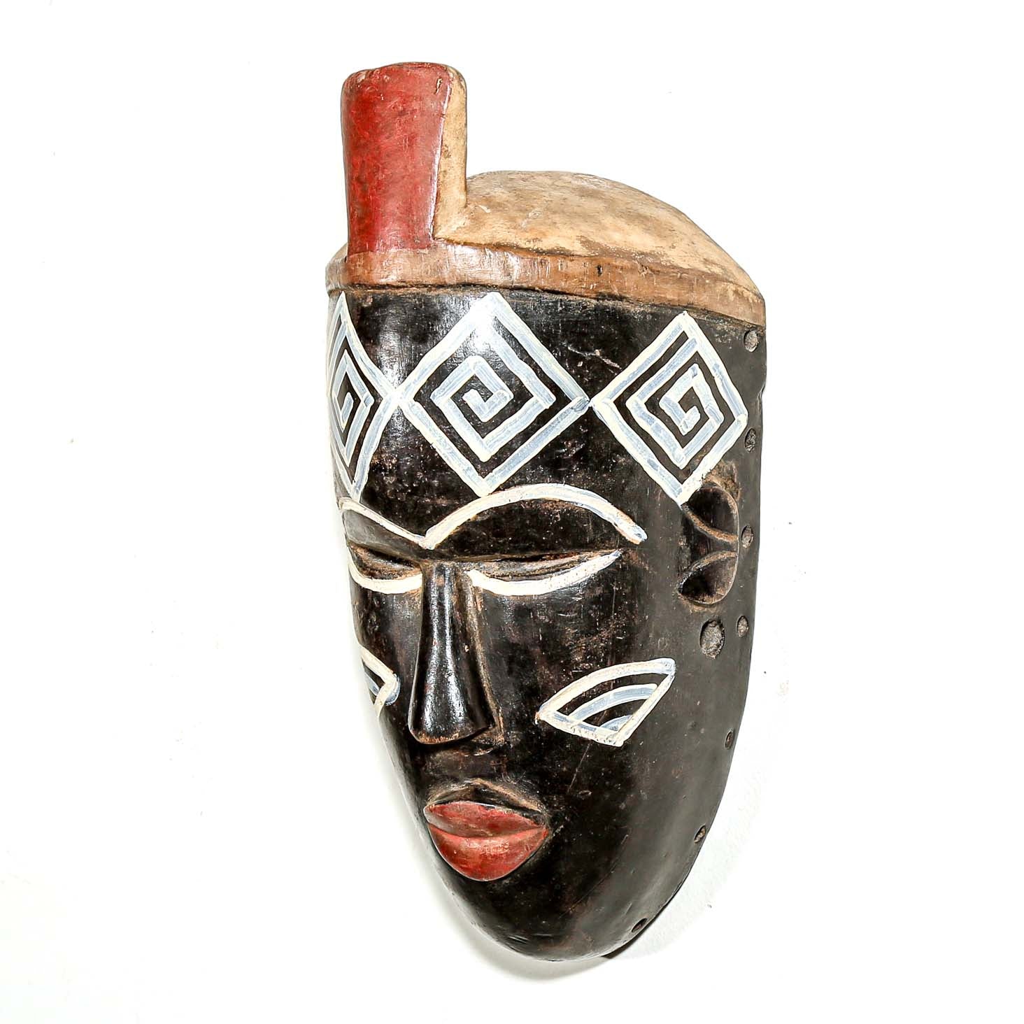 Wooden mask from Nigeria by a Nigerian artist with black, white, and red design on a white background