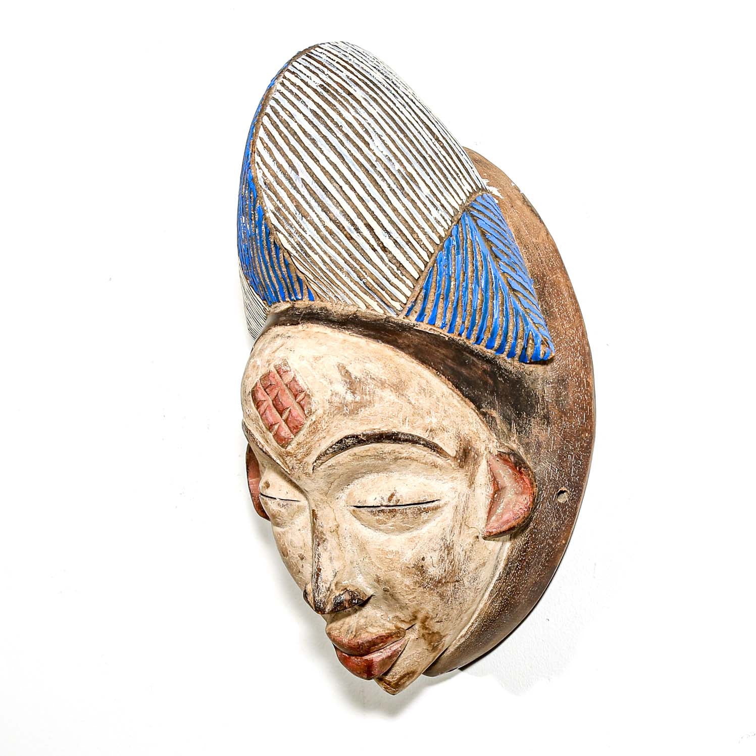 Traditional wooden mask from Africa with blue and silver headdress on a white background