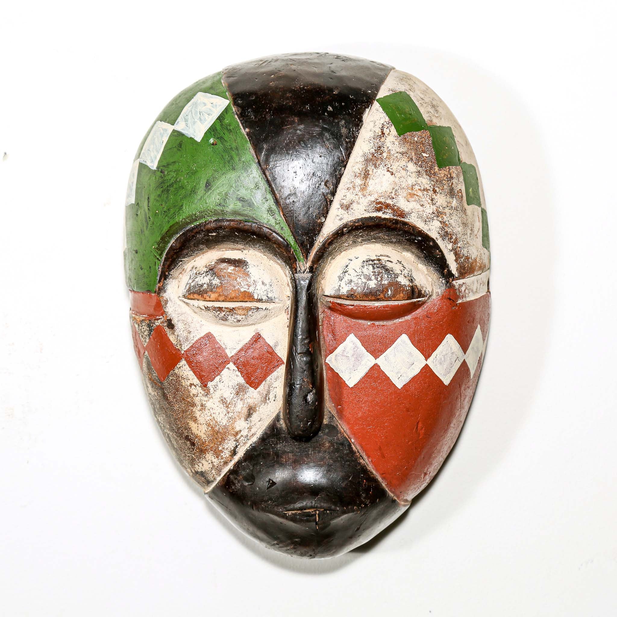 Colorful Aduma African wood mask with geometric patterns on a white bedroom wall