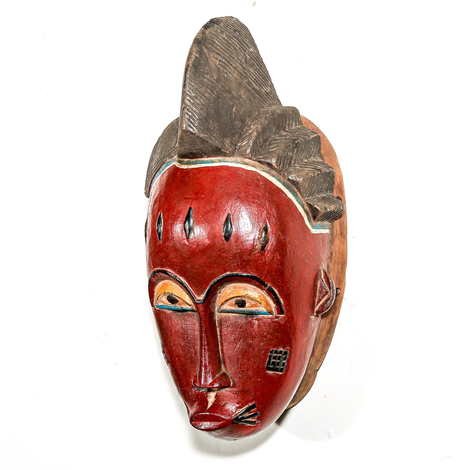 Wooden mask with red face and decorative elements on a white background