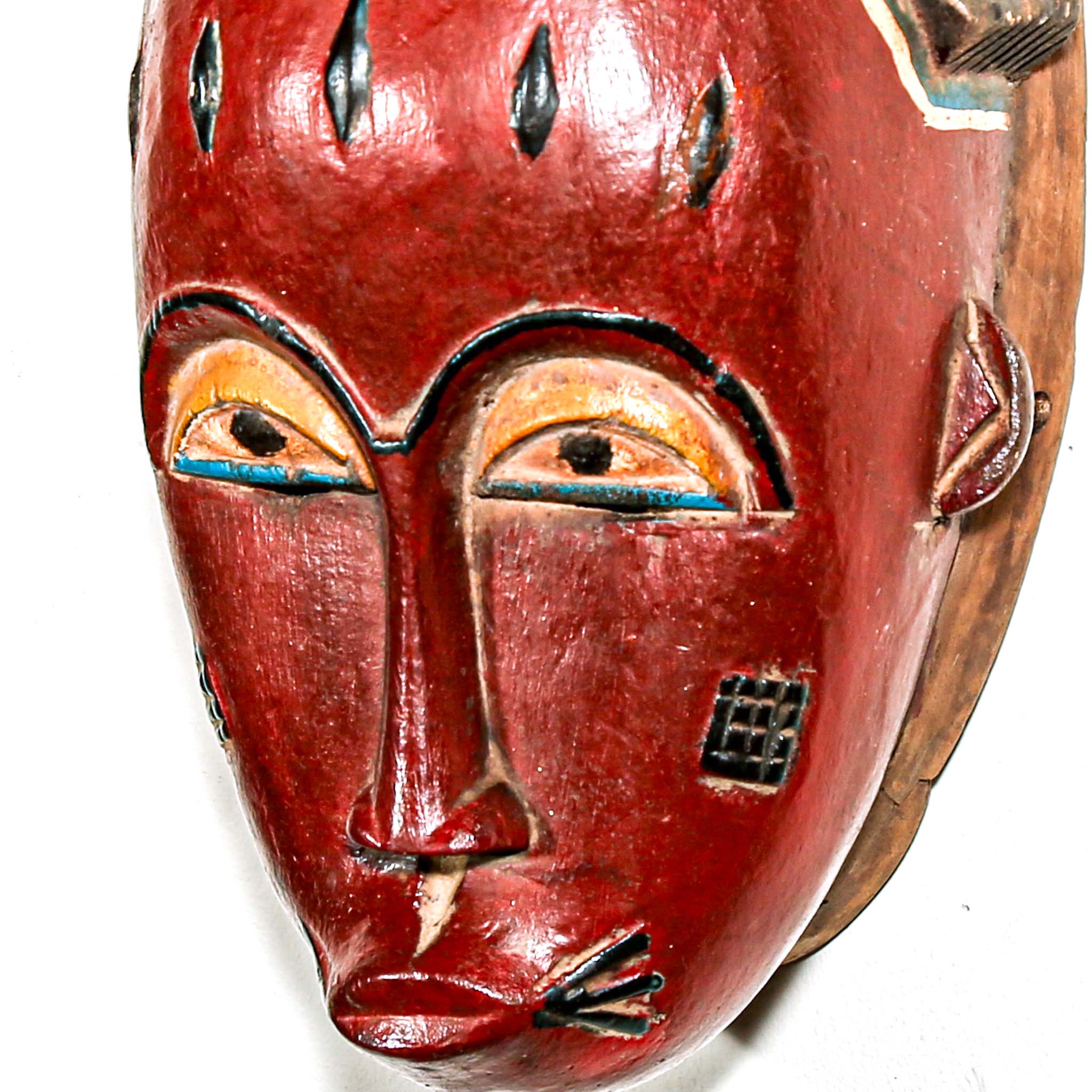African-style mask with red face and decorative headdress on a white background