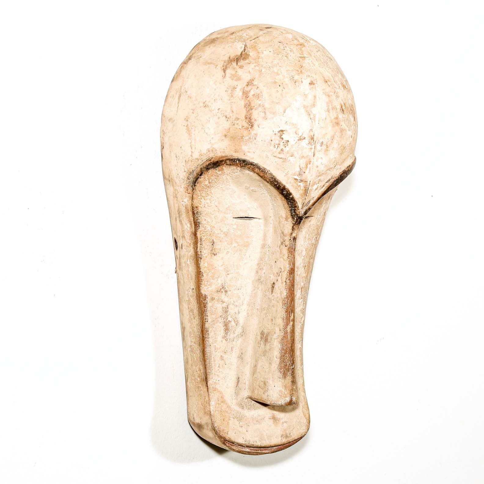 Decorative white African Fang tribe carved wood mask resembling a stylized face on a white background