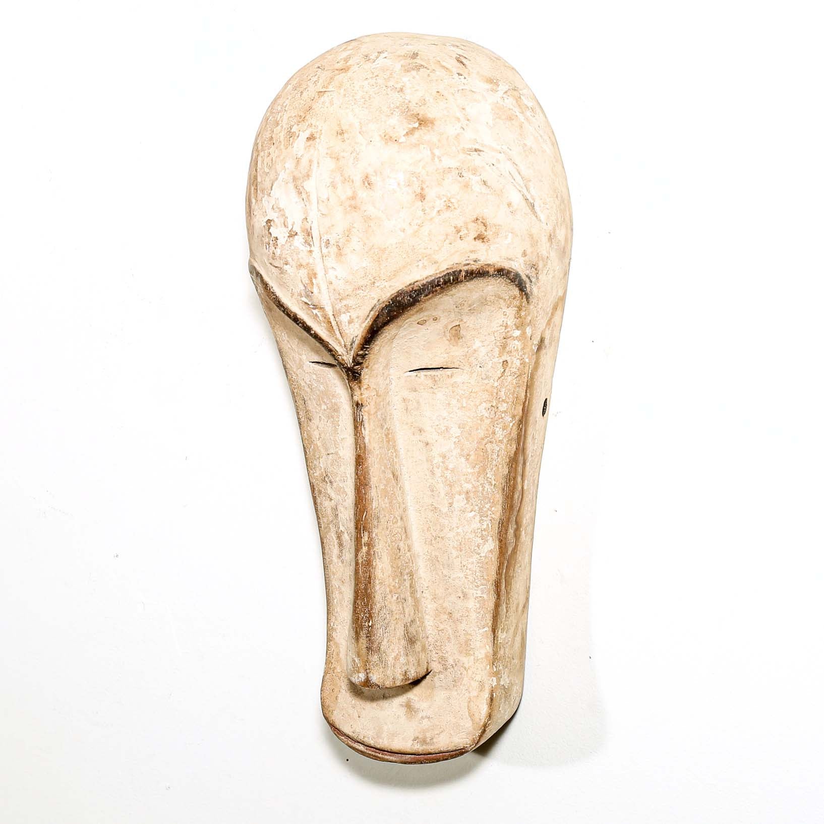 Decorative white African Fang tribe carved wood mask resembling a stylized face on a white background
