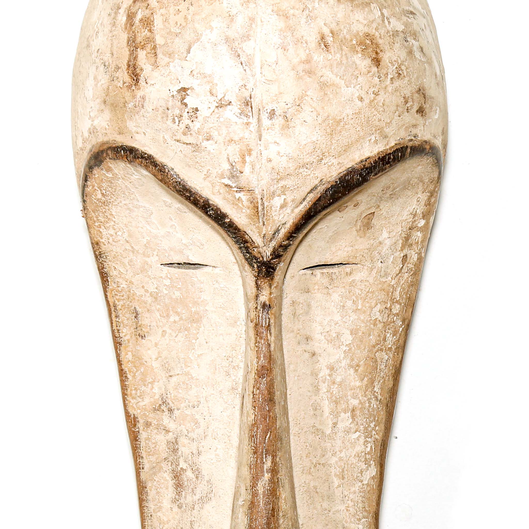 Decorative white African Fang tribe carved wood mask resembling a stylized face on a white background