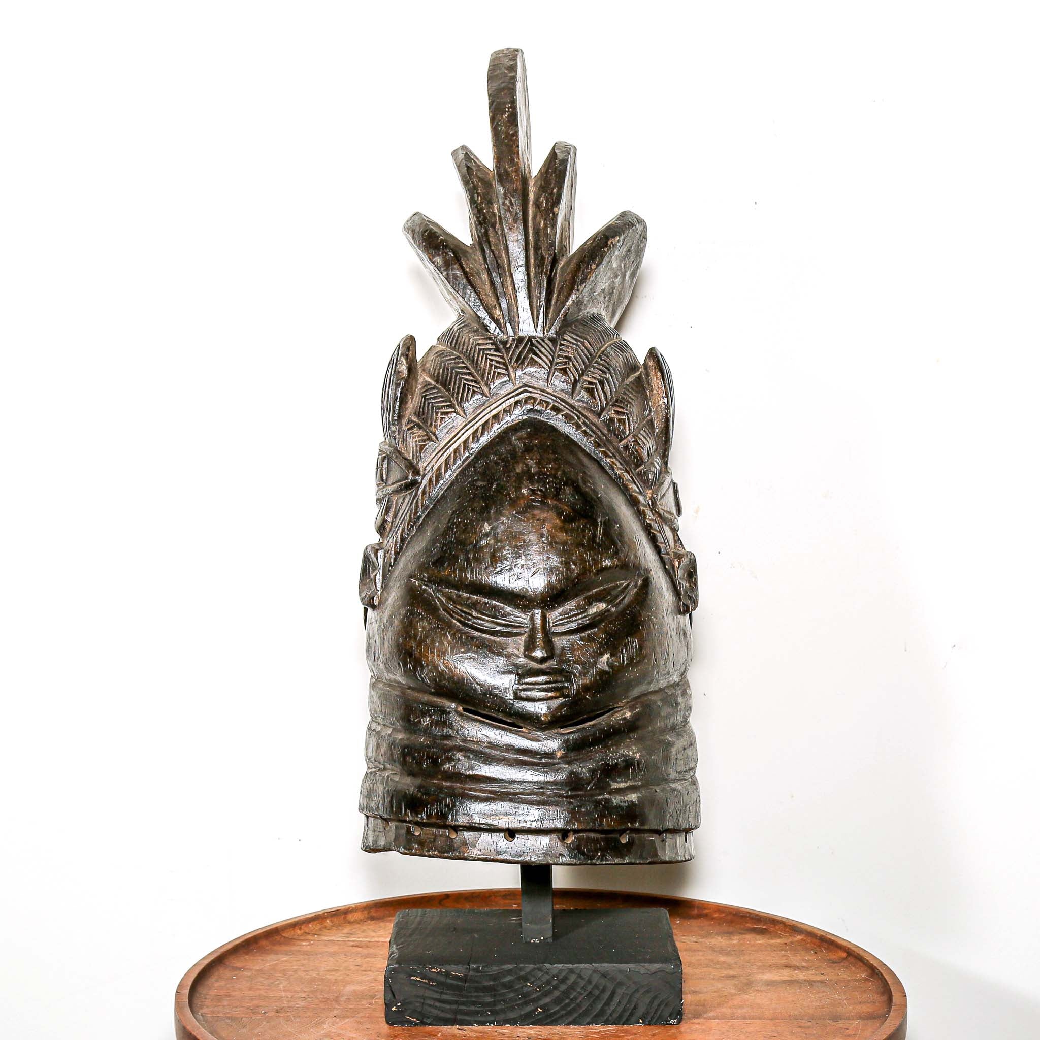 Decorative black african mask on a wooden home side table against a white background